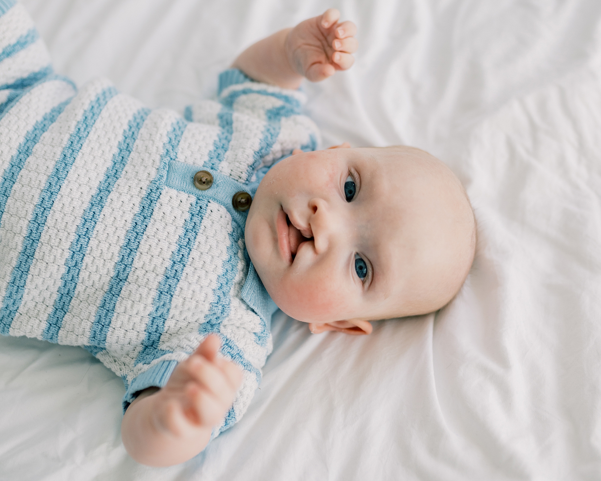 baby boy with cleft palette looks up in white and blue knit sweater