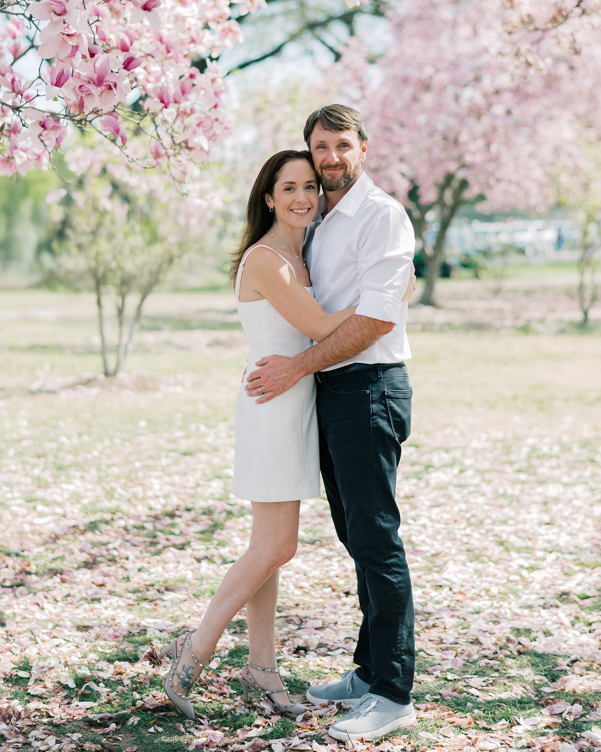couple hugs under pink blossoms in Washington DC