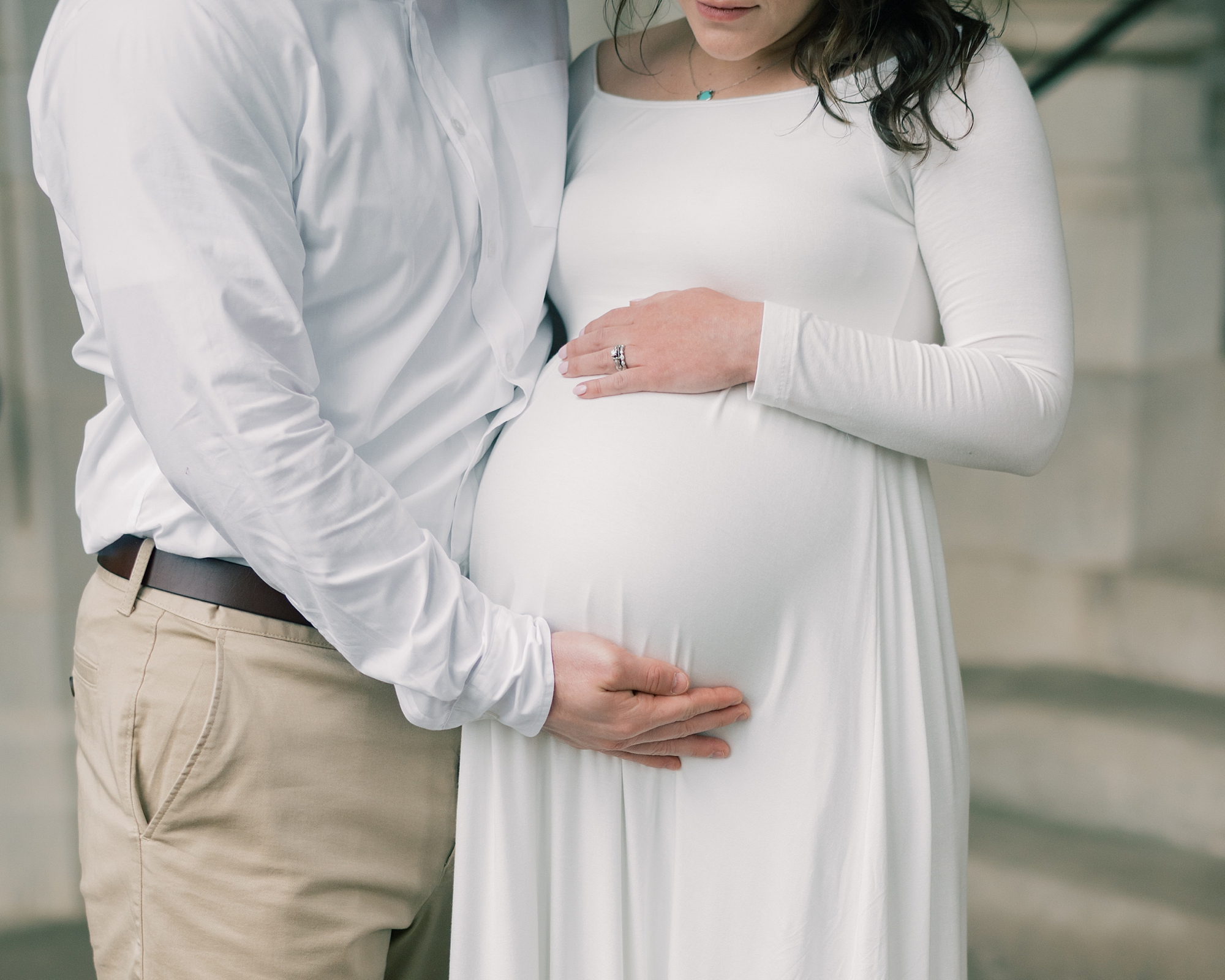 couple hugs and holds mom's baby bump during maternity session at the Washington National Cathedral