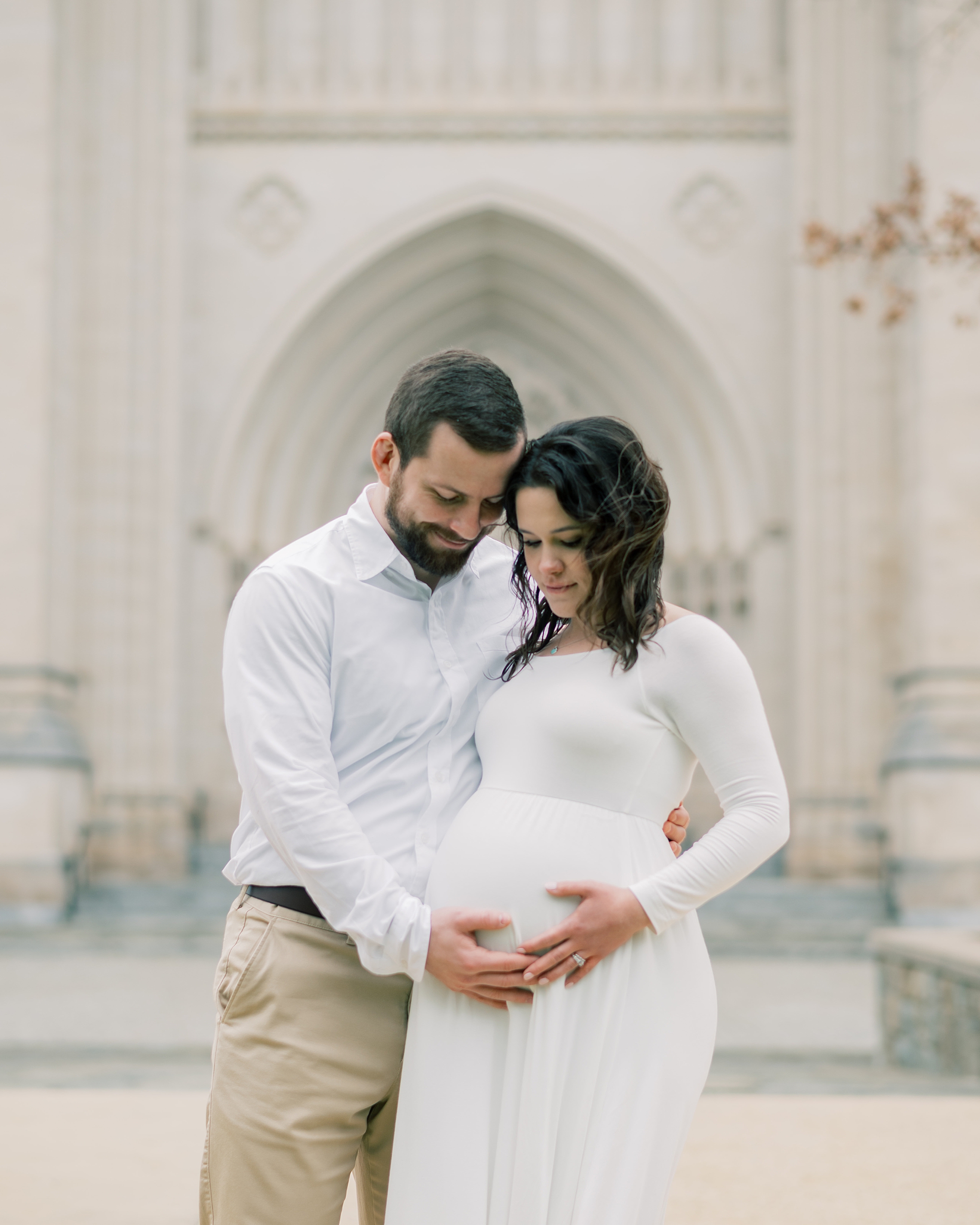 expecting couple holds hands on baby bump outside the Washington National Cathedral