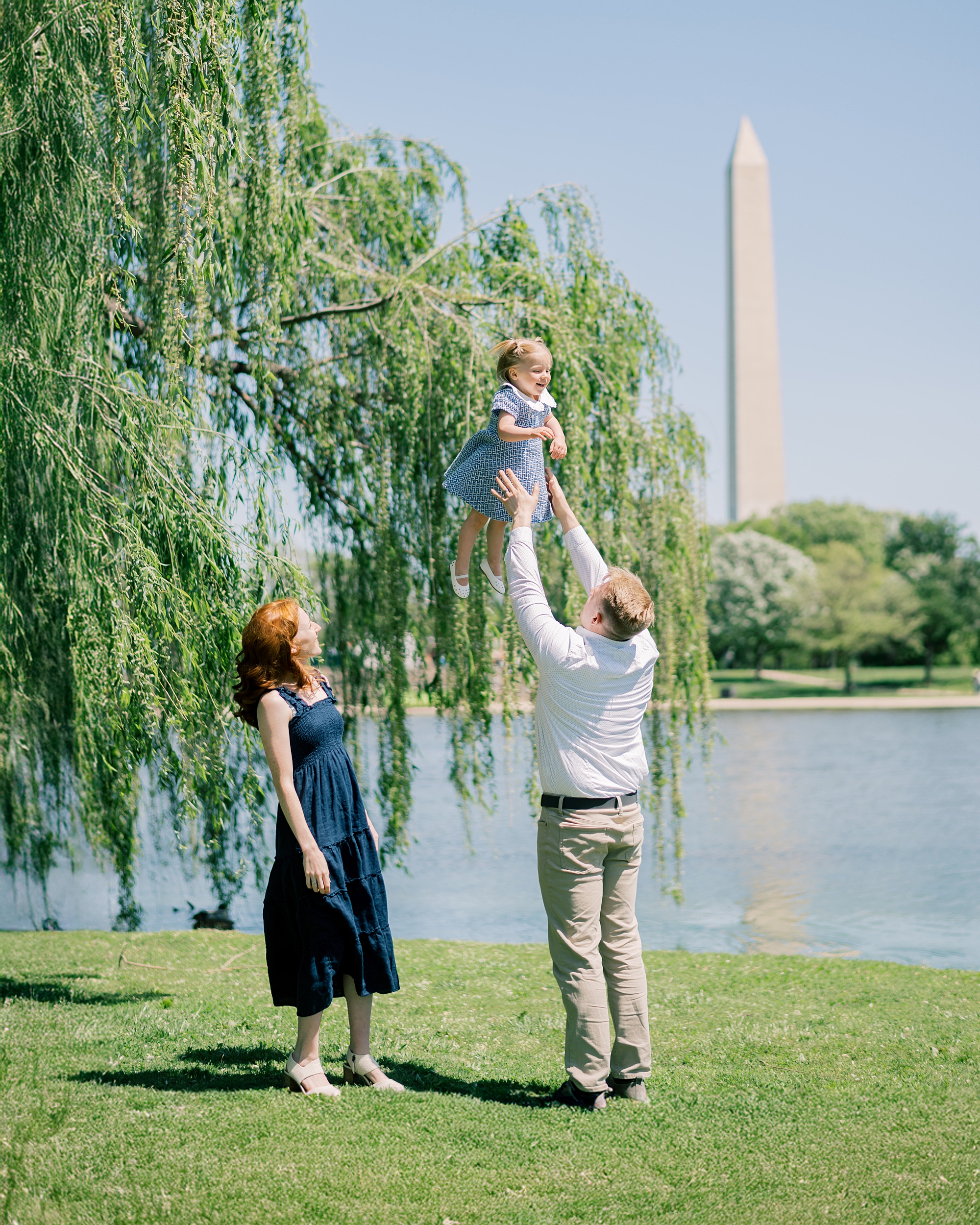 dad tosses daughter in the air during DC family photos near Washington Monument
