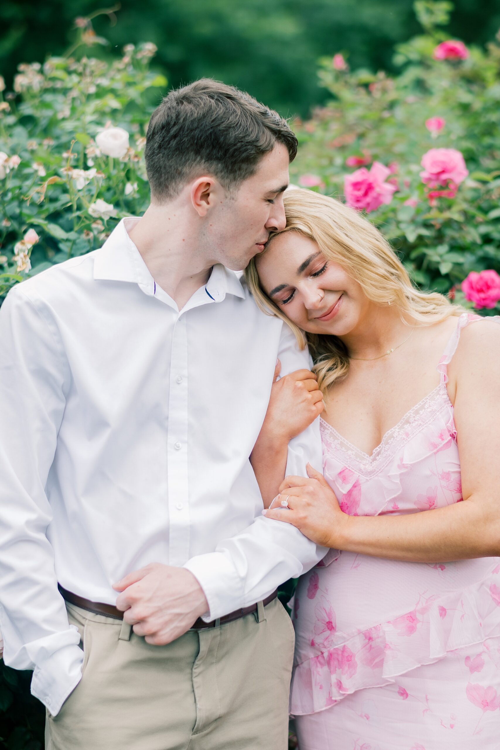 blonde woman lays head on man's shoulder during garden engagement session in Arlington VA