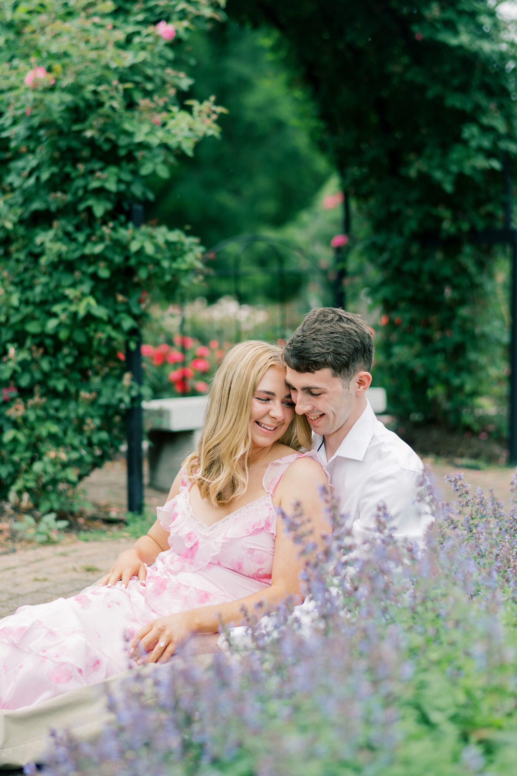 couple sits together by lavender during garden engagement session in Arlington VA