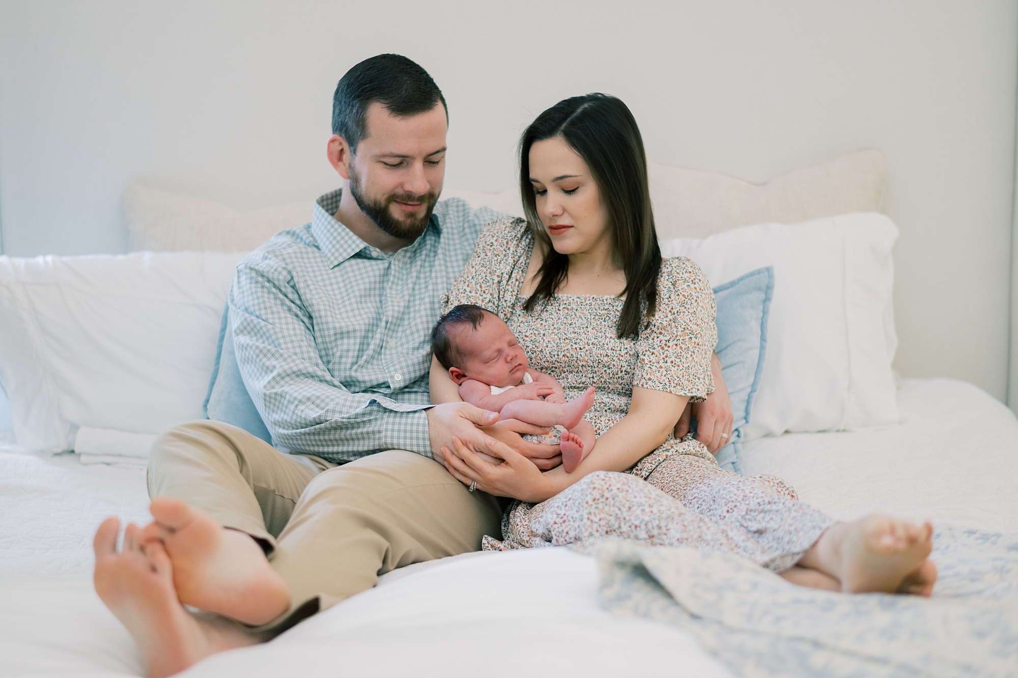 parents sit on bed holding newborn daughter during lifestyle newborn session at home in Washington DC