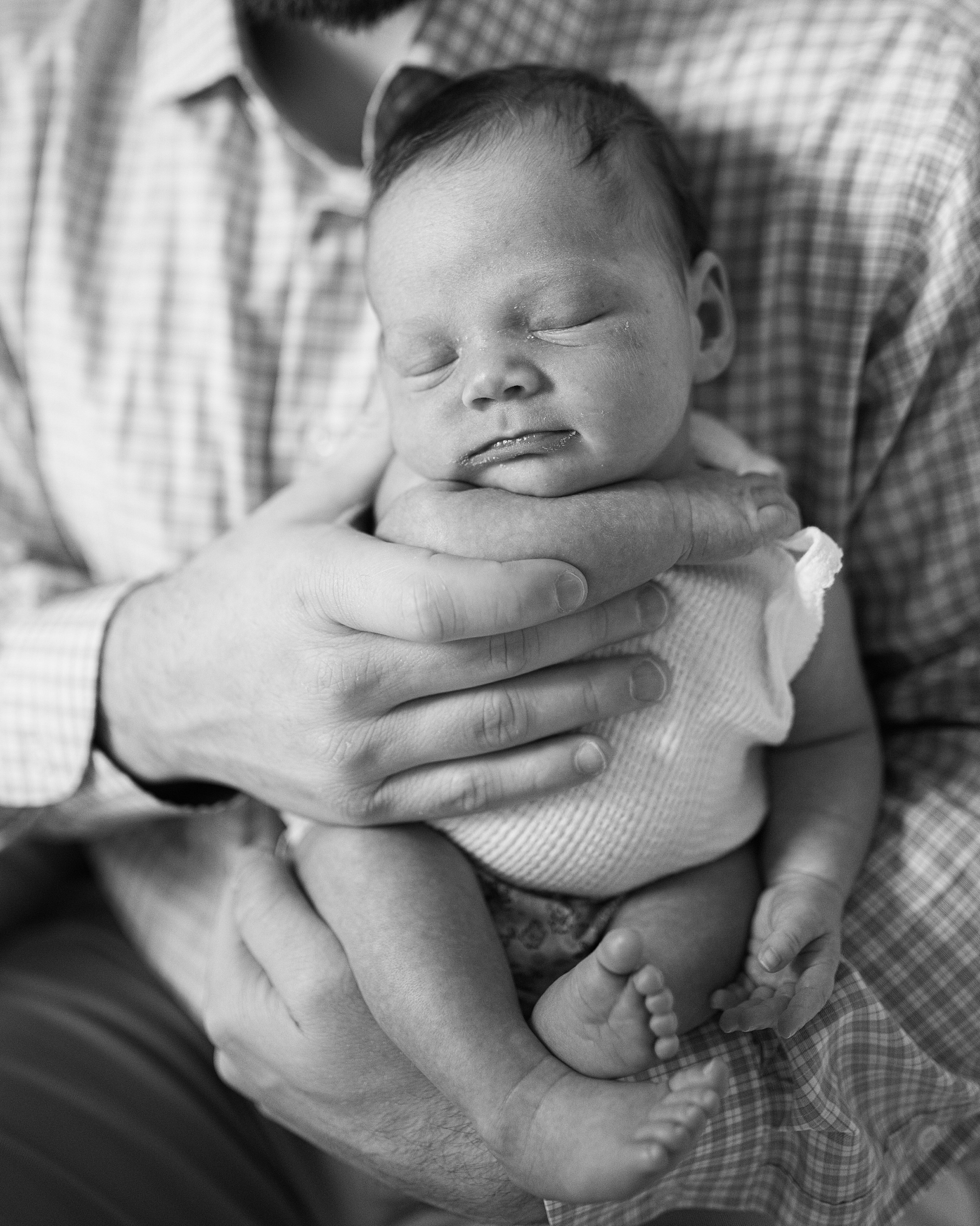 dad holds baby girl in front of his chest