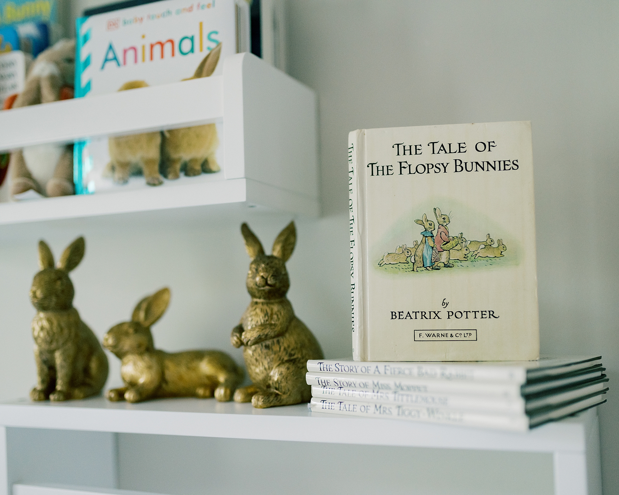 gold rabbits sit on bookshelf with Peter Rabbit books