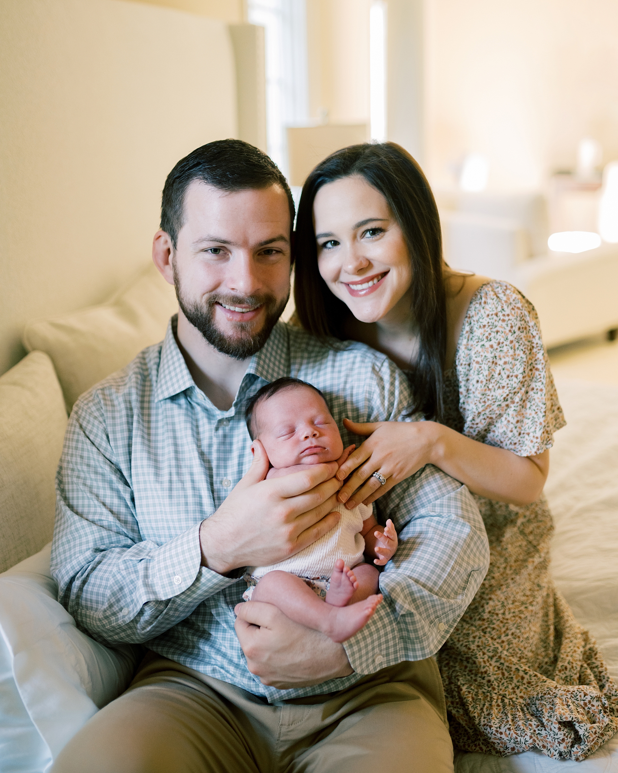 parents snuggle with newborn baby girl in their laps during newborn session at home in Washington DC