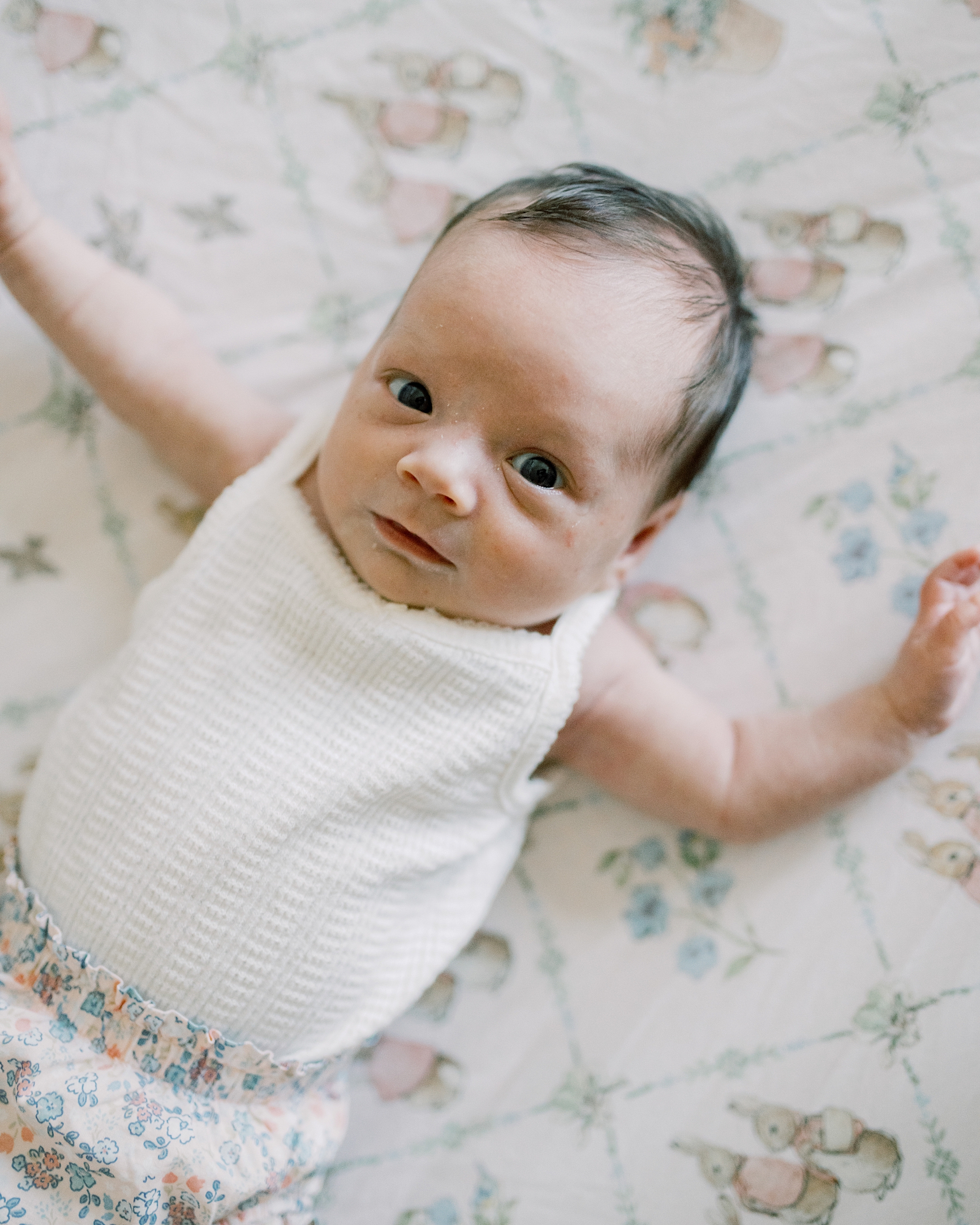 baby girl stretches out on pastel Peter Rabbit sheets