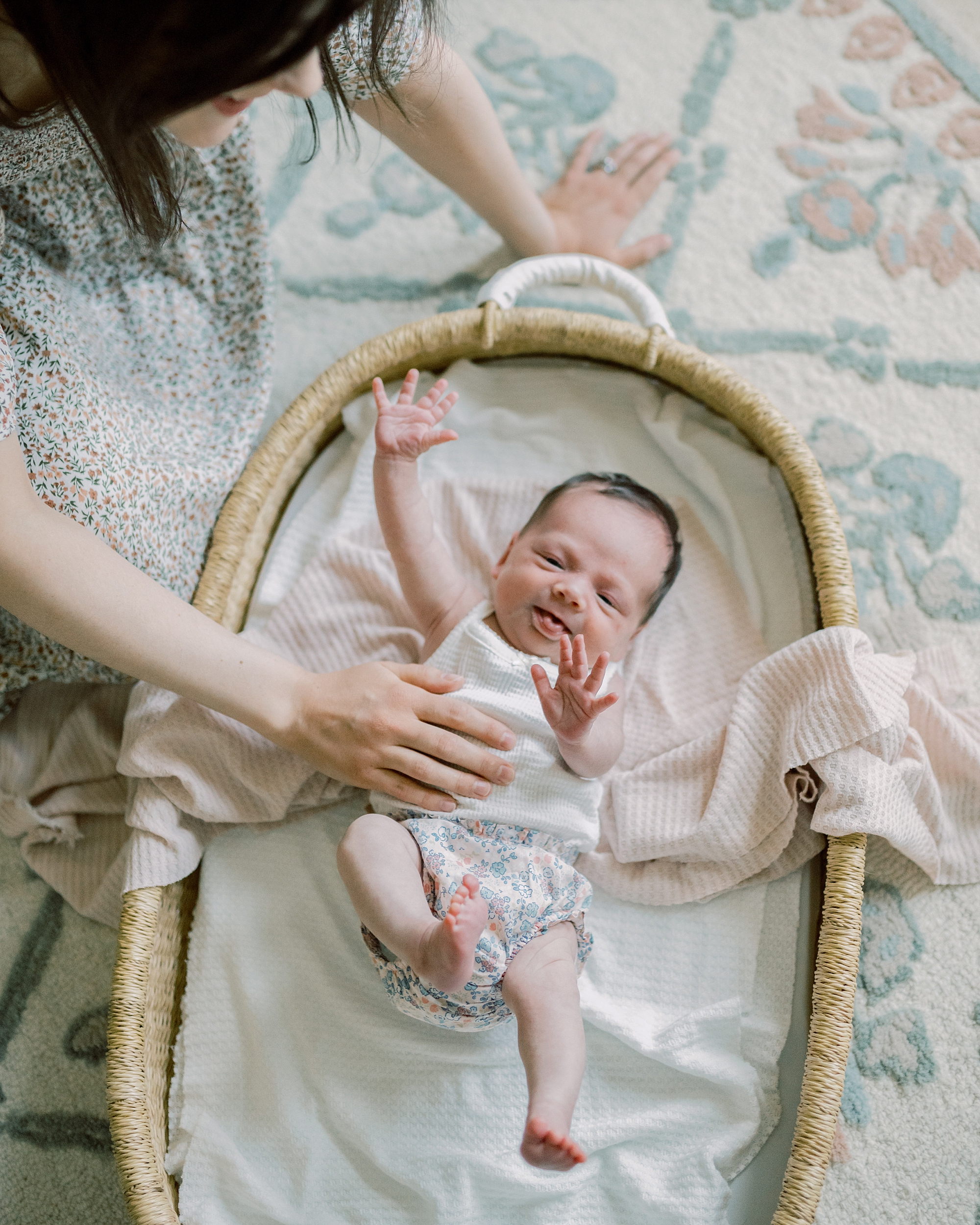 baby reaches out of Moses basket during newborn session at home in Washington DC