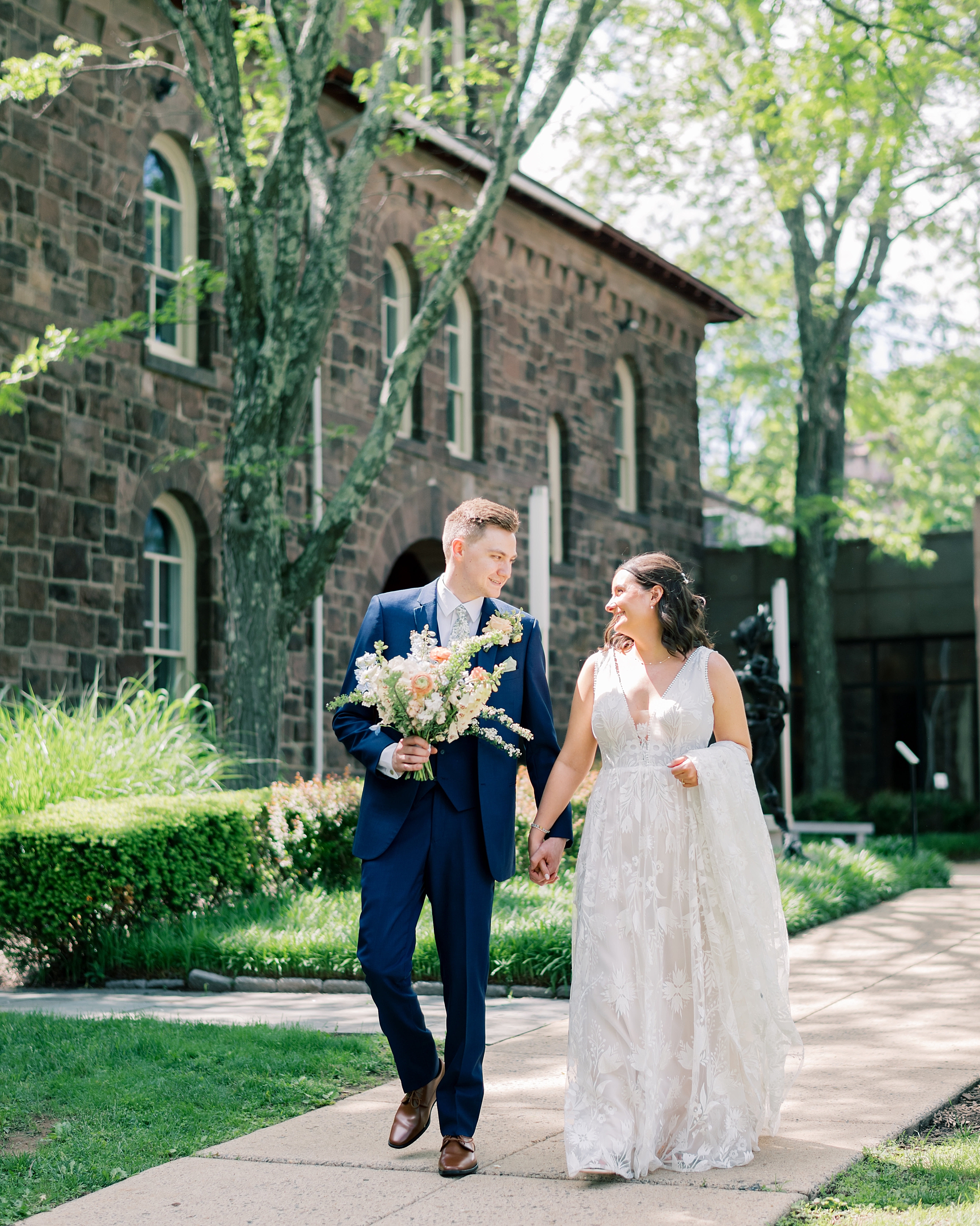 couple holds hands walking down sidewalk at Terrain Gardens