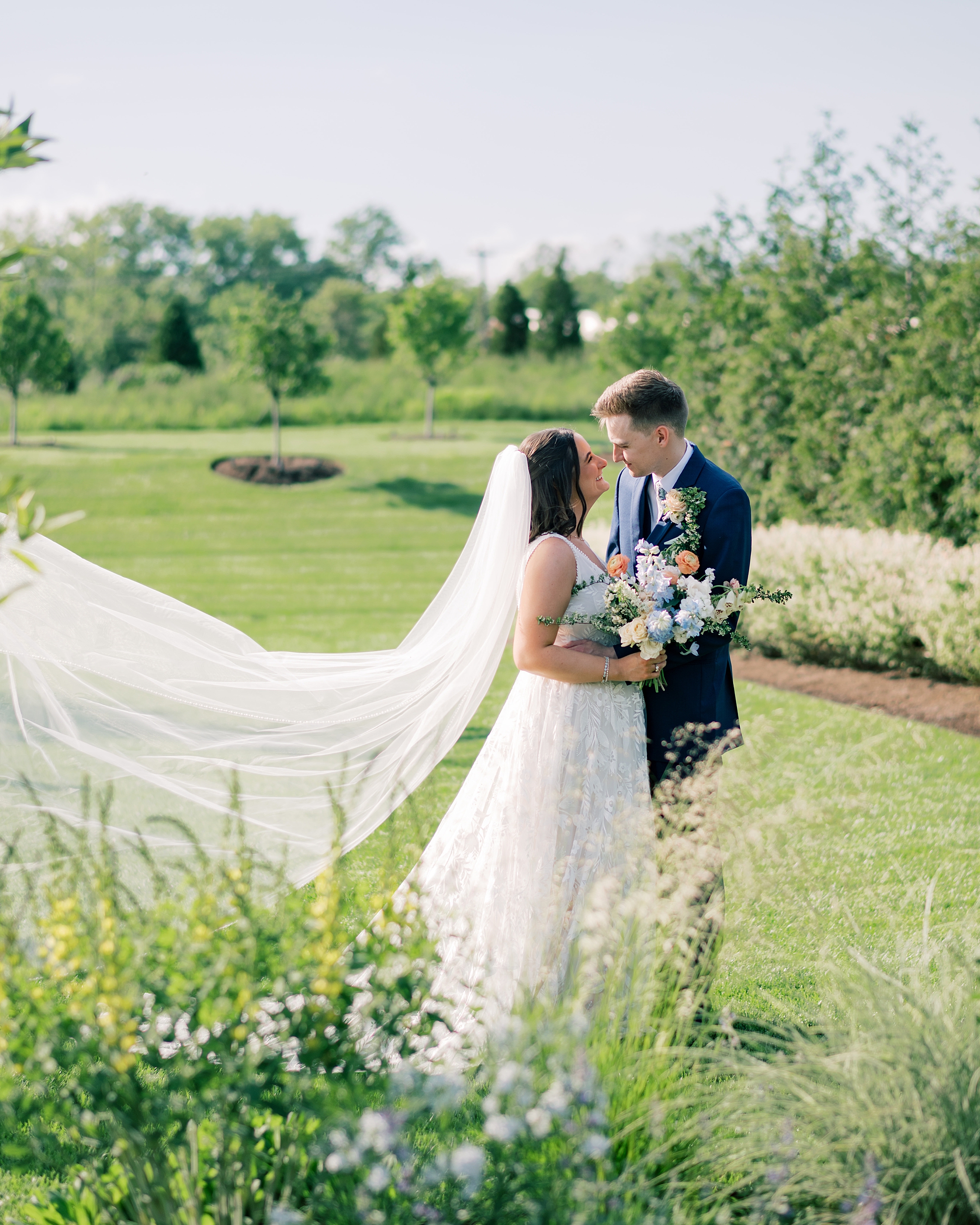 bride and groom stand together in field at Terrain Gardens