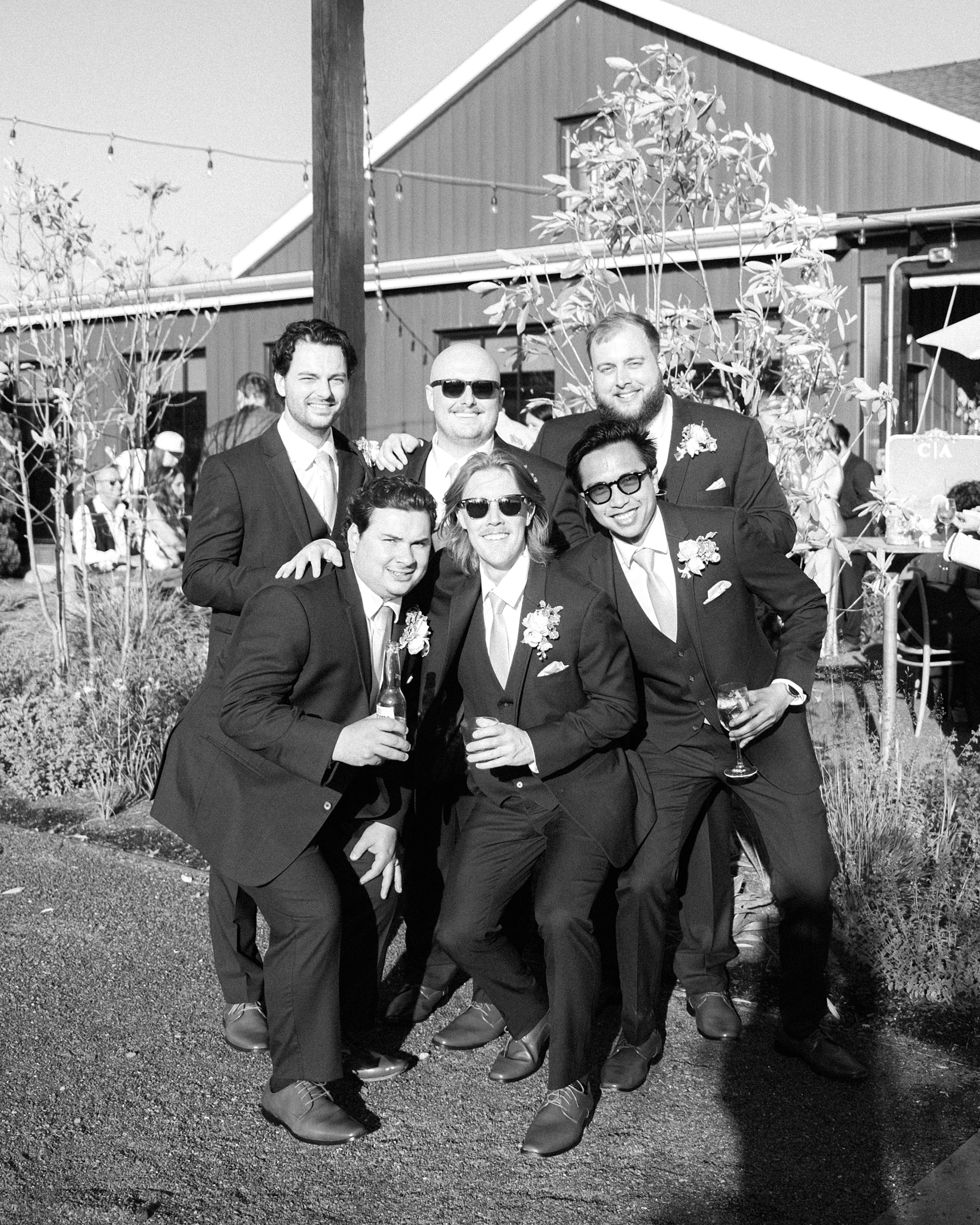 groomsmen pose around groom in suits and sunglasses at Terrain Gardens