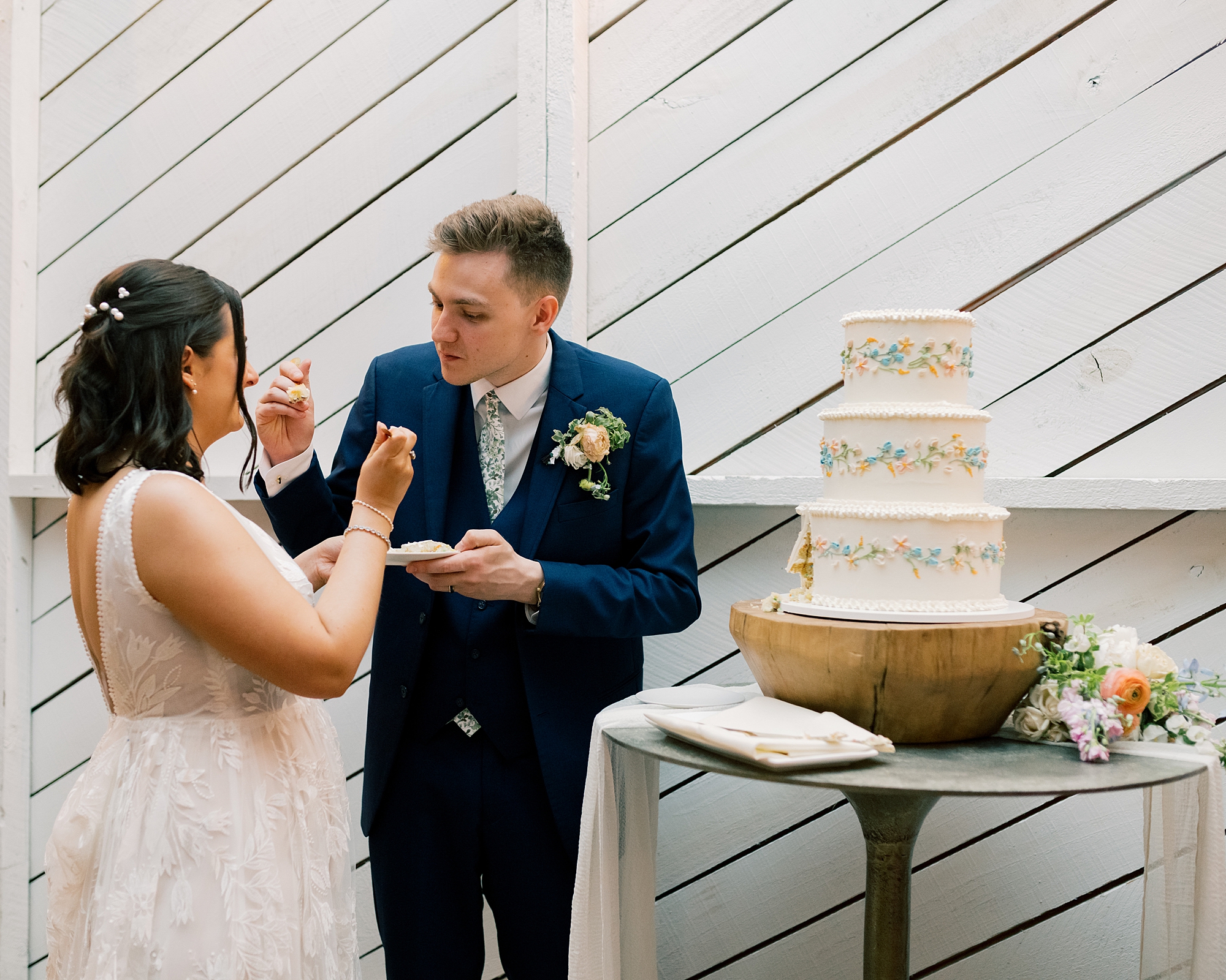 bride and groom cut and feed each other cake at reception