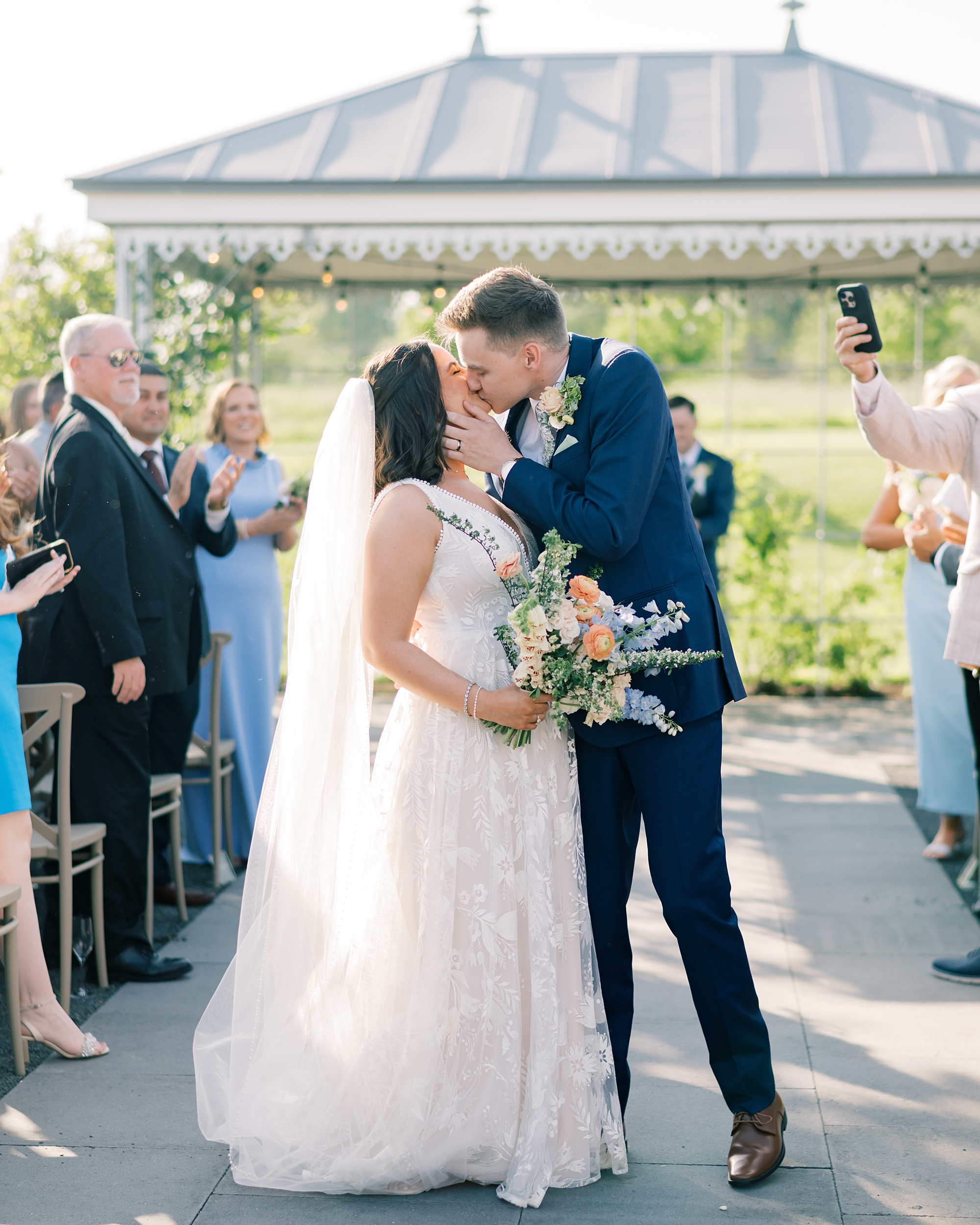 bride and groom kiss in aisle of ceremony at Terrain Gardens
