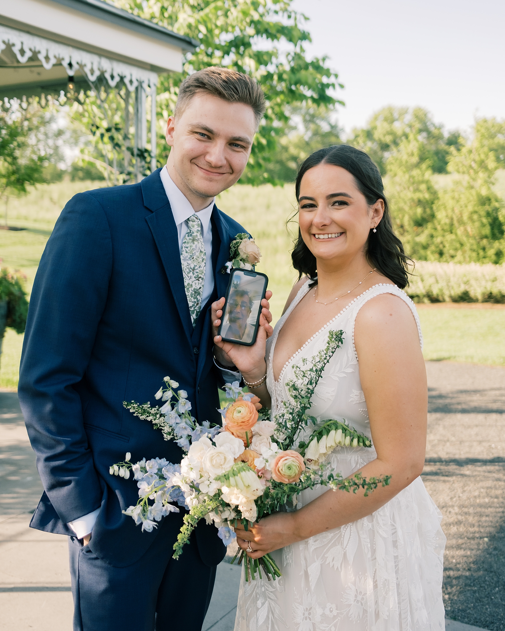 bride and groom smile holding phone for guest