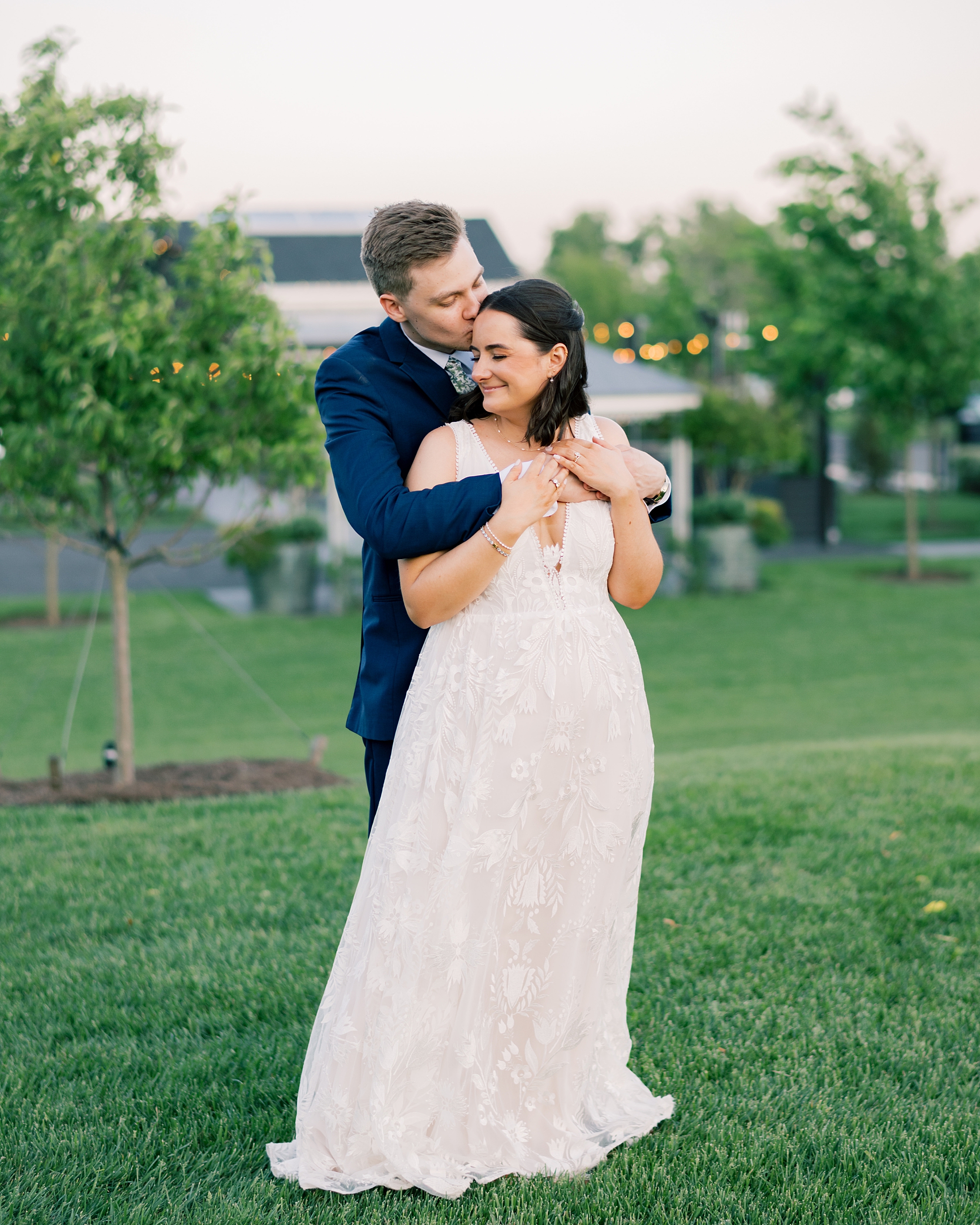 groom hugs bride from behind on lawn at Terrain Gardens