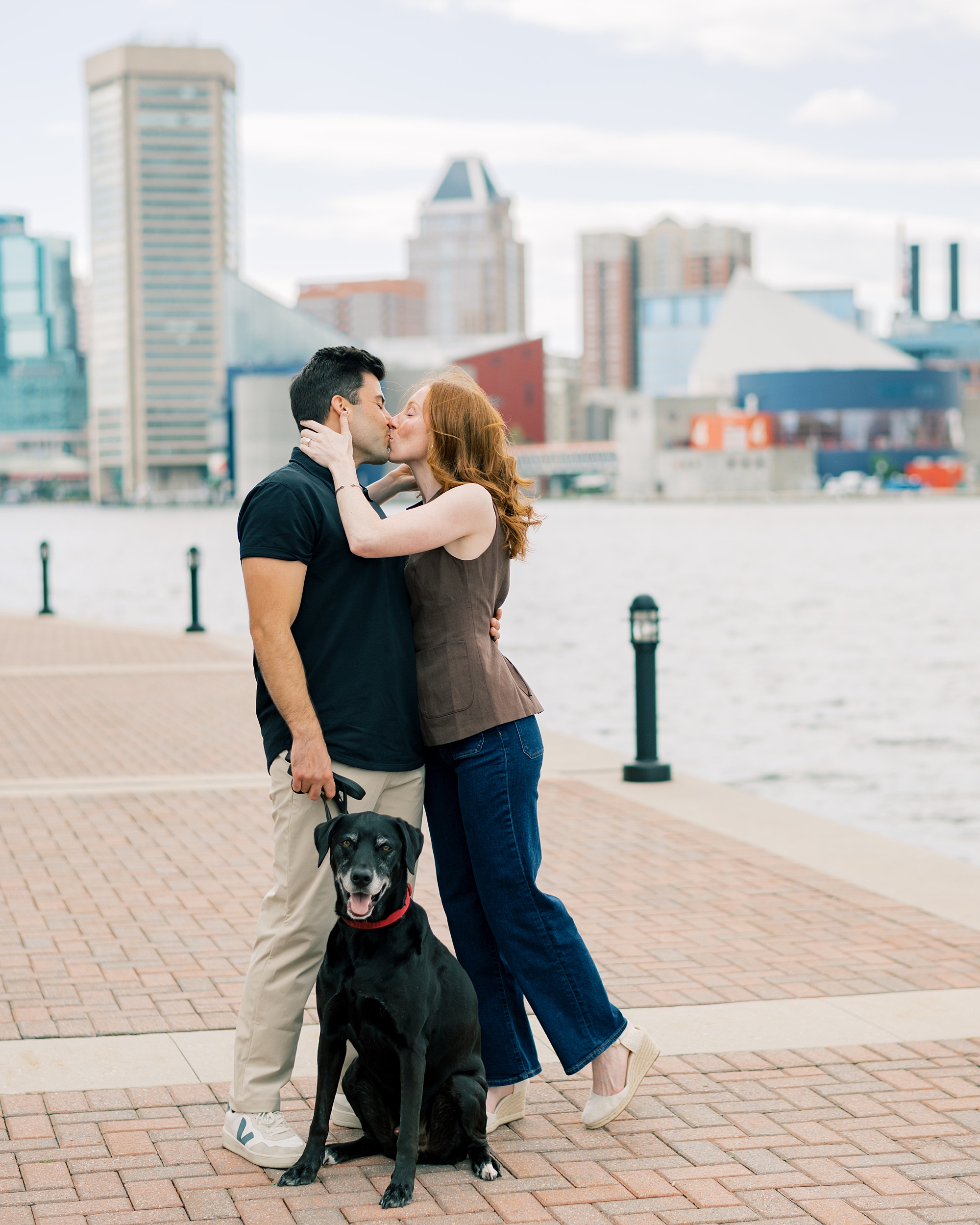man and woman smile together with dog in Baltimore Inner Harbor