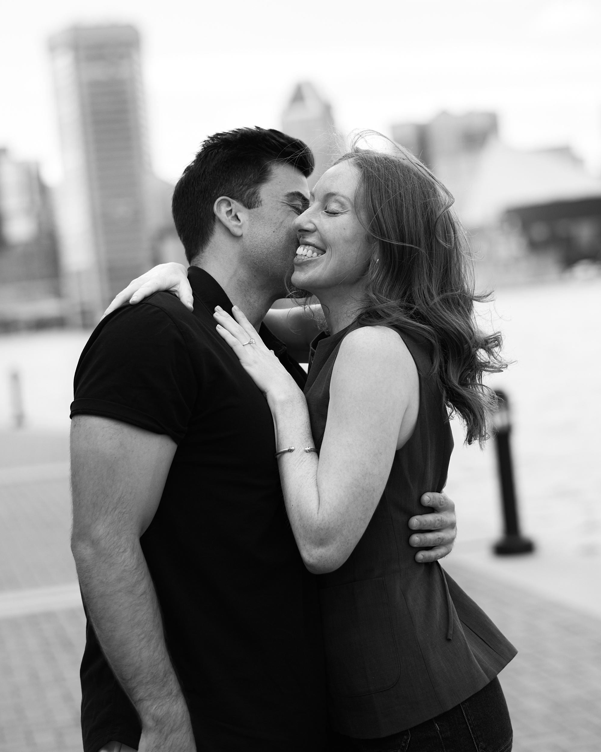 engaged couple hugs along waterfront after proposal in Baltimore Maryland