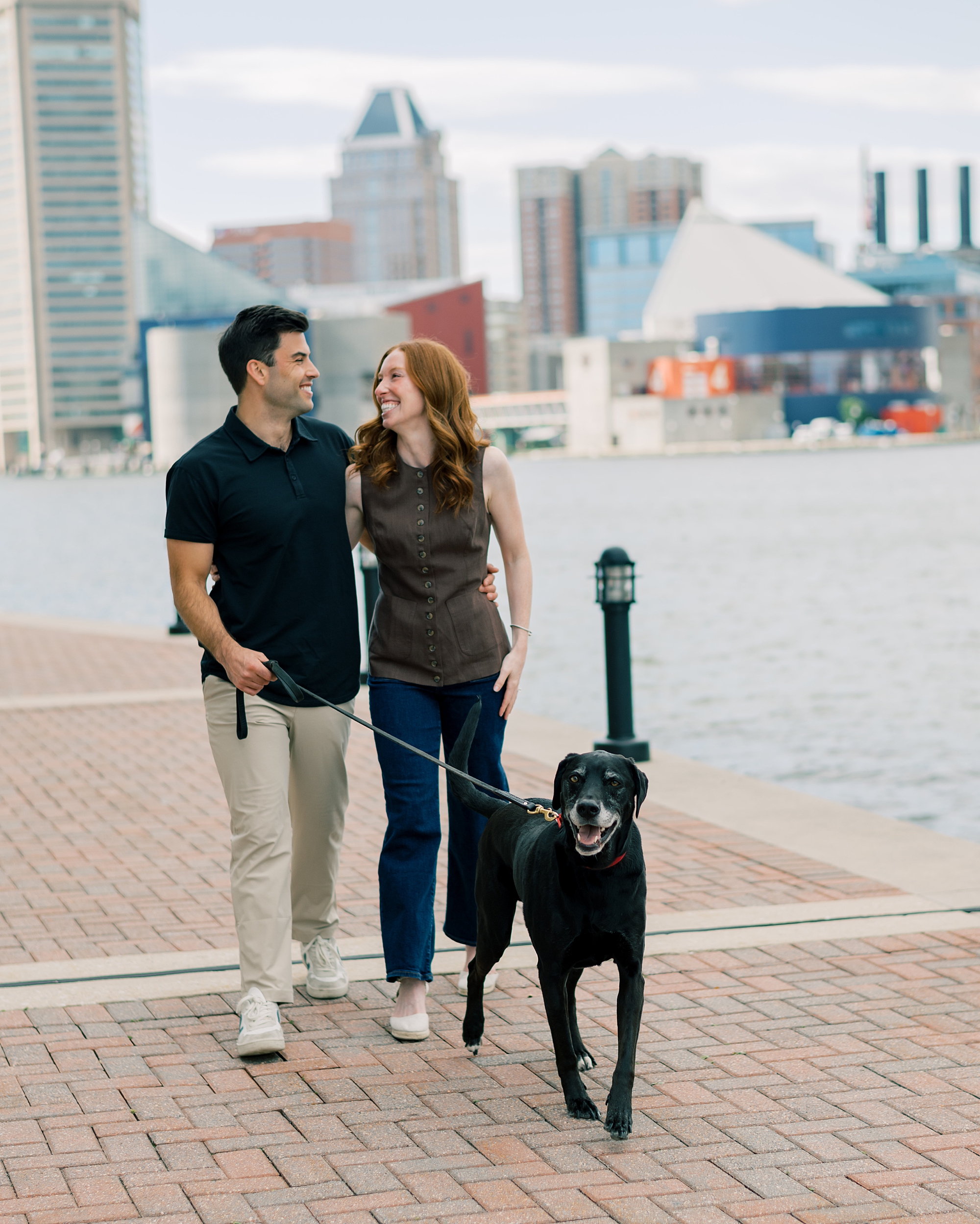 man and woman walk dog along waterfront in Baltimore MD