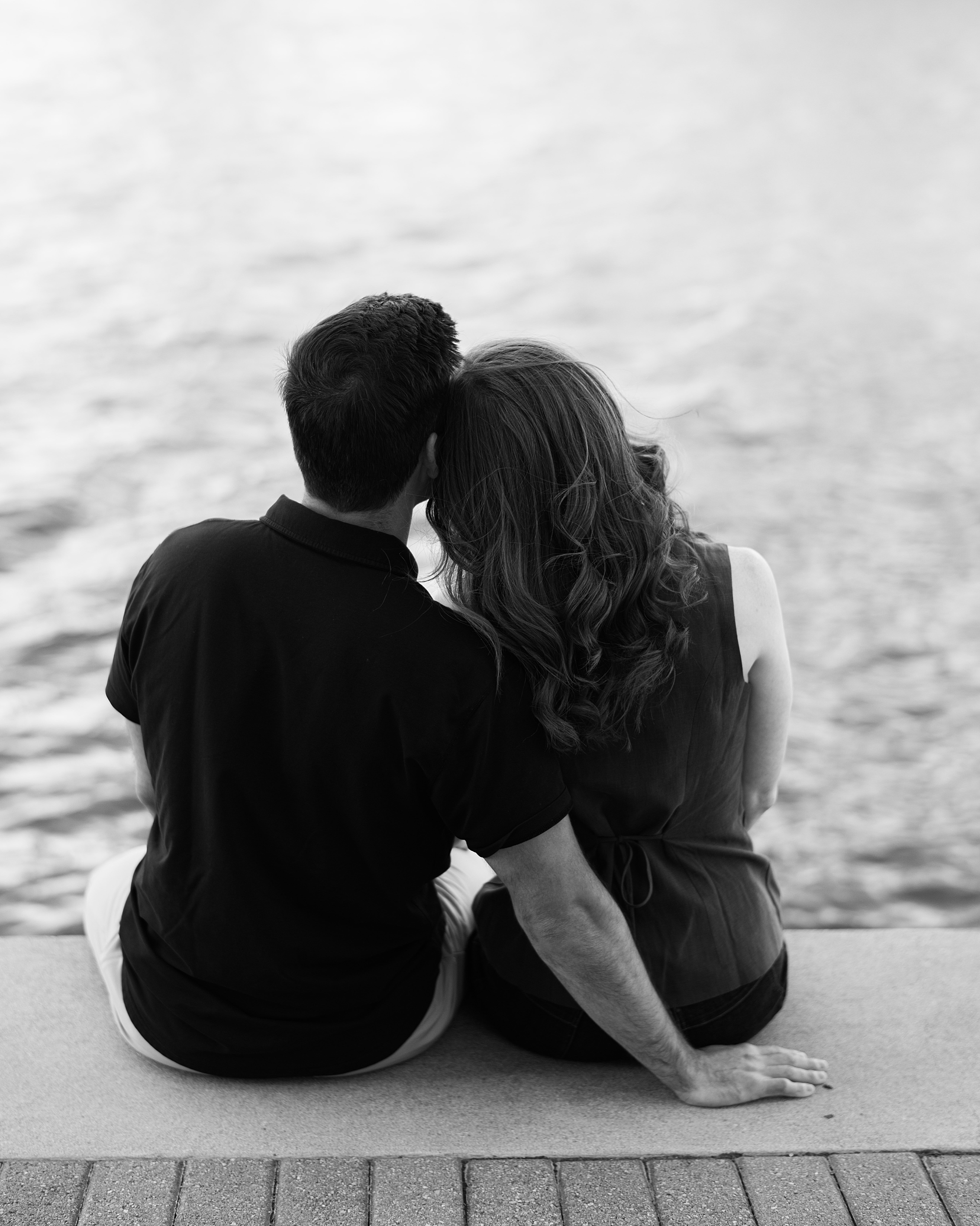man and woman sit together on wooden dock in Baltimore MD