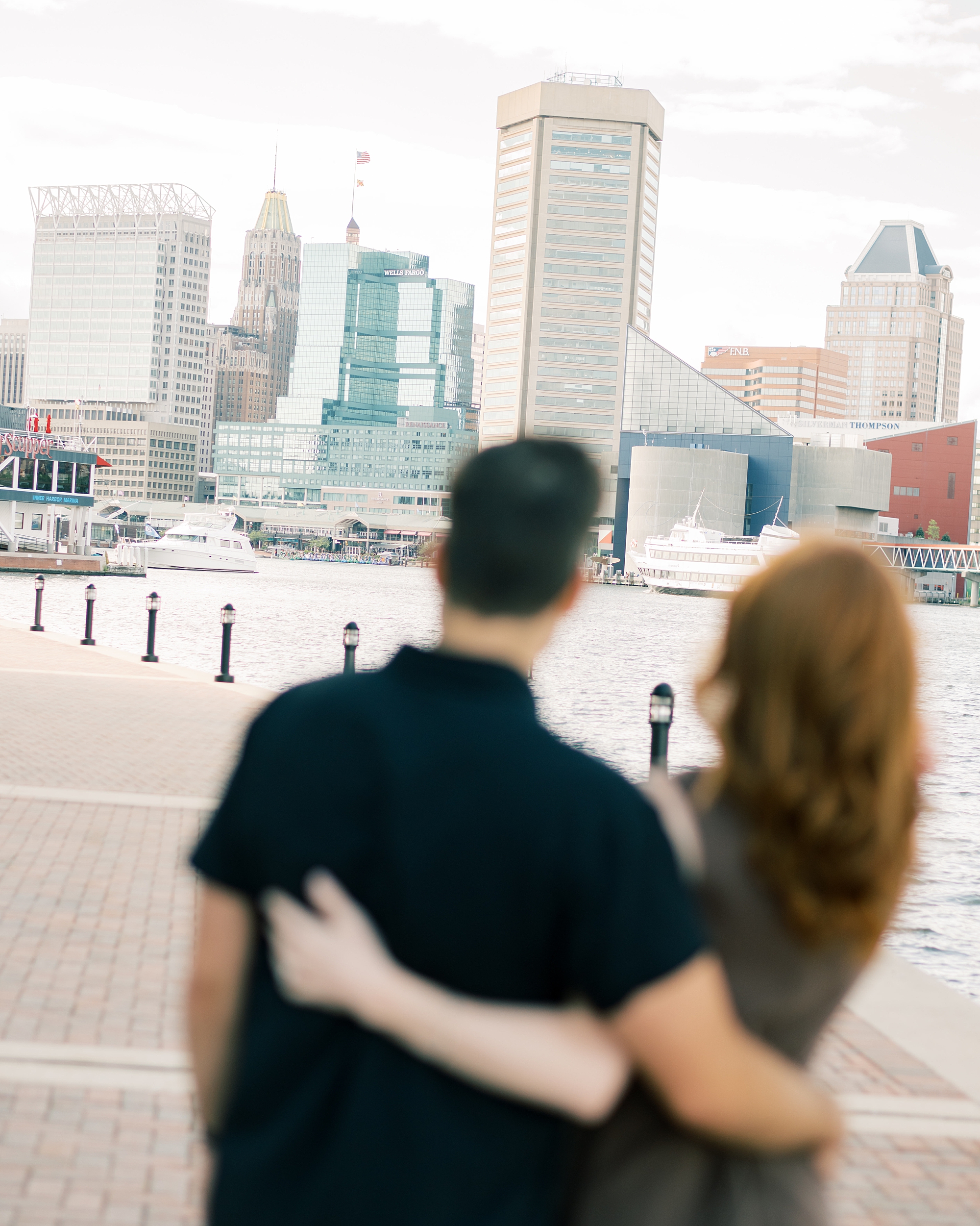 man and woman hug looking at Baltimore skyline