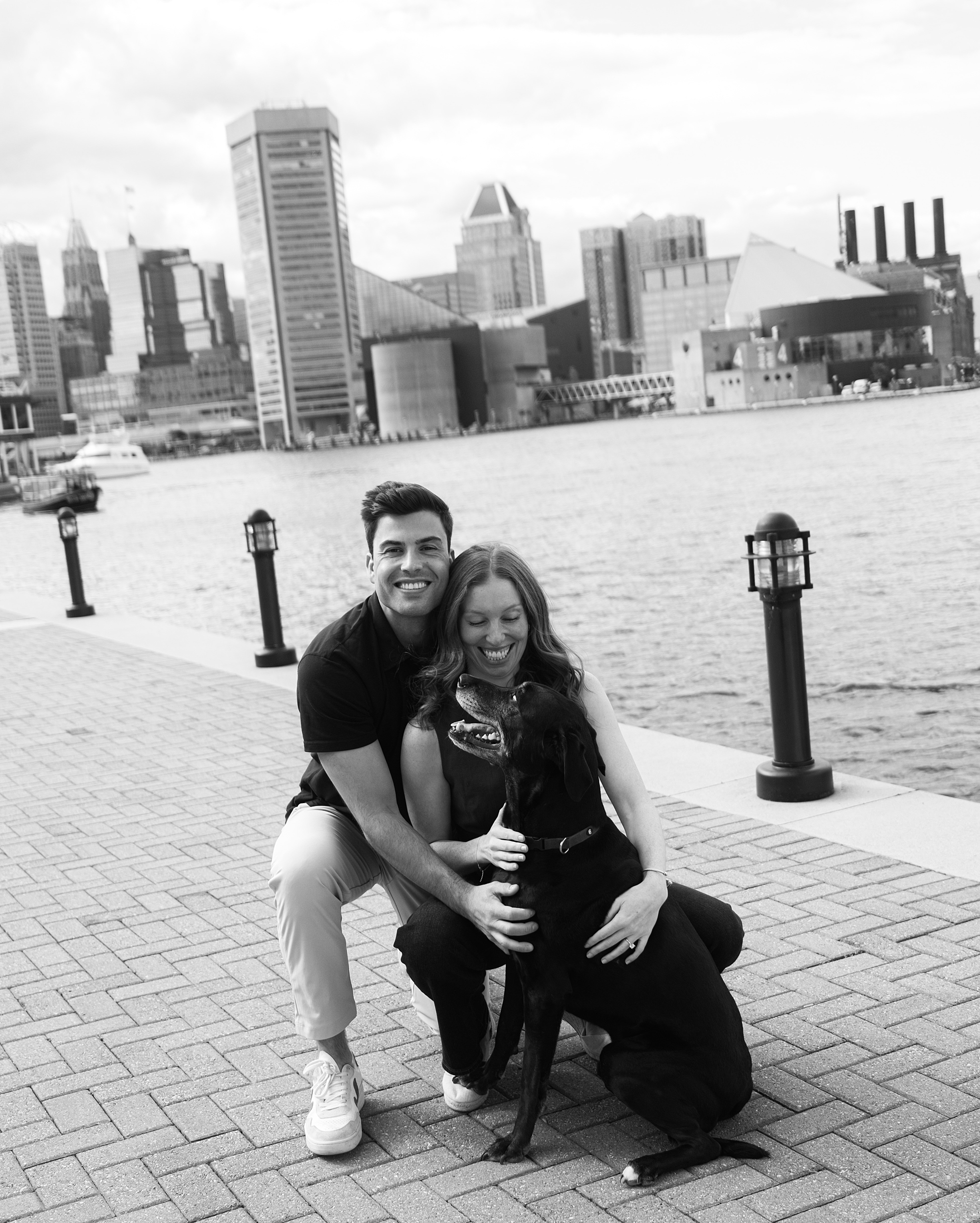 man and woman kneel with dogs along waterfront in Baltimore