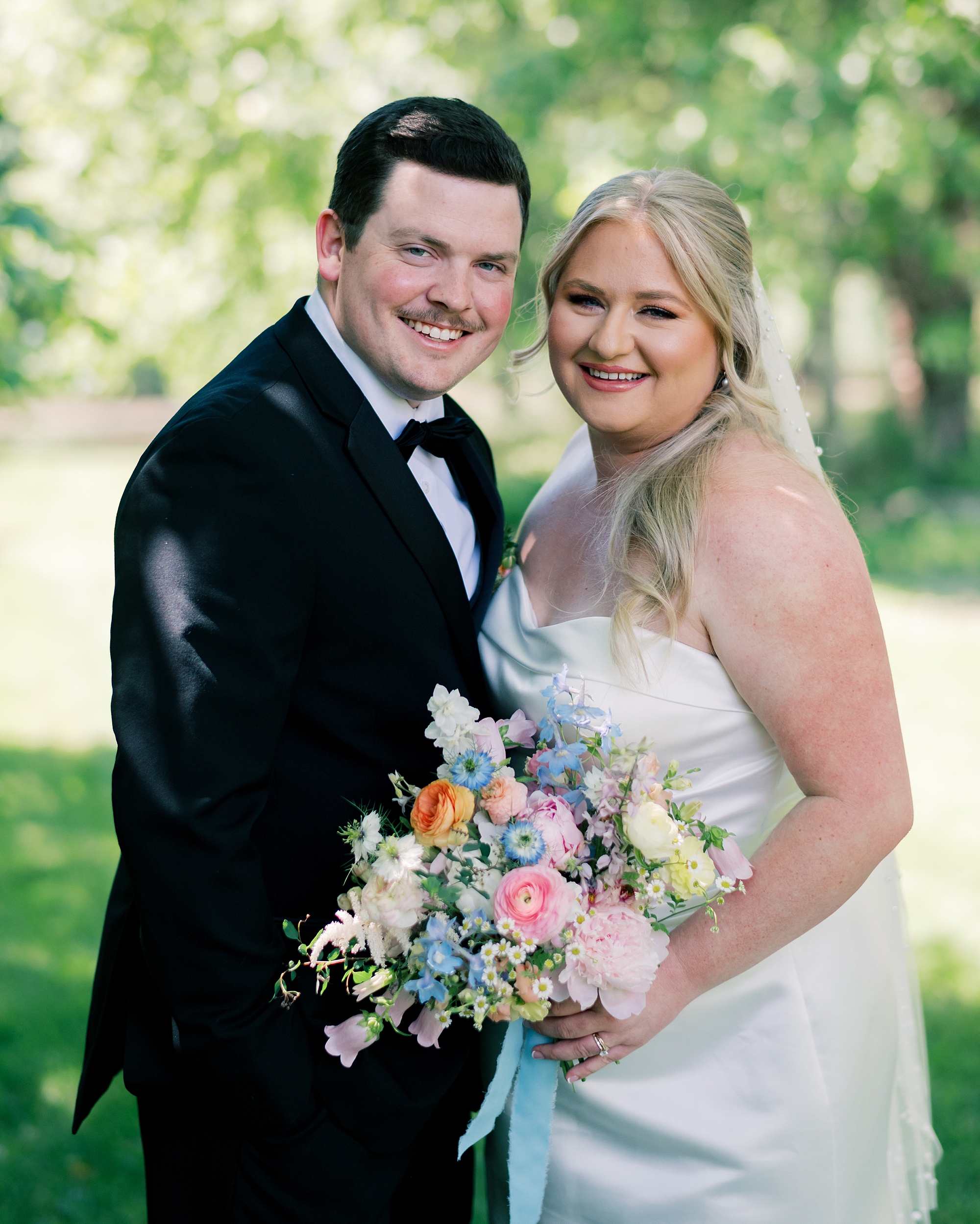 bride and groom hug in shade near trees at Olde Breton Inn
