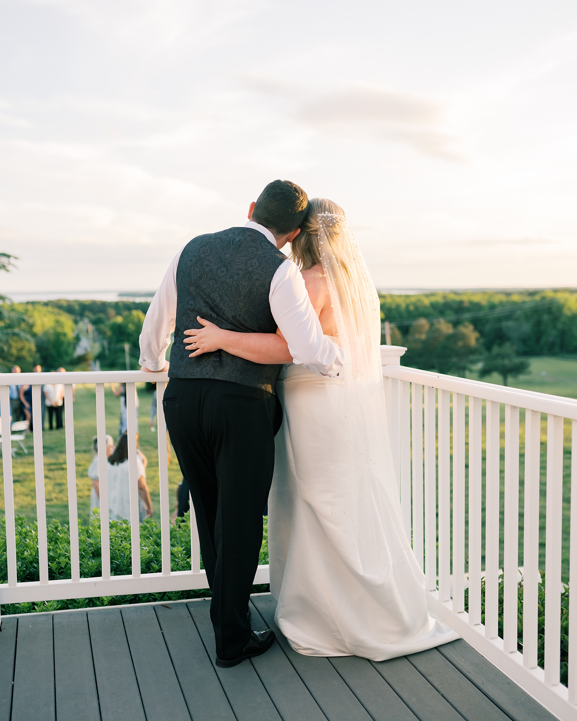 newlyweds hug leaning heads together on porch overlooking Olde Breton Inn