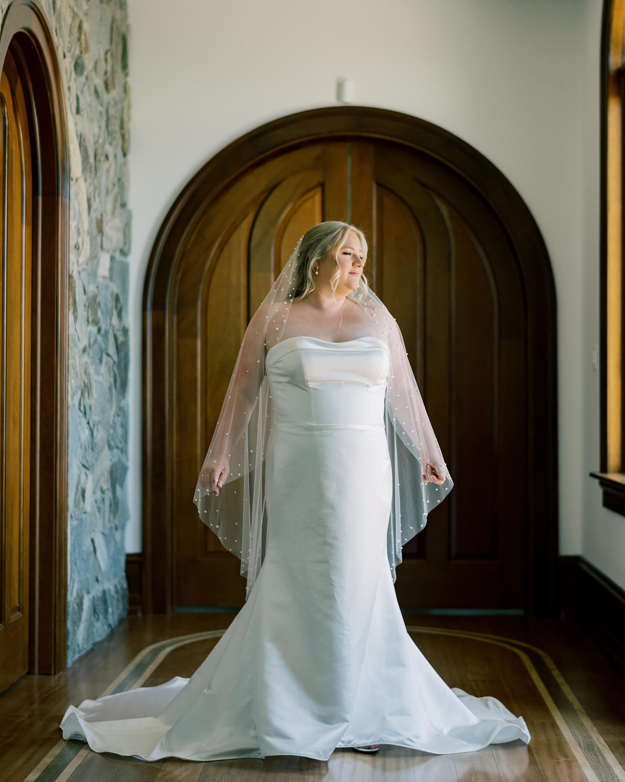 bride stands in doorway at Olde Breton Inn with veil pulled out behind her