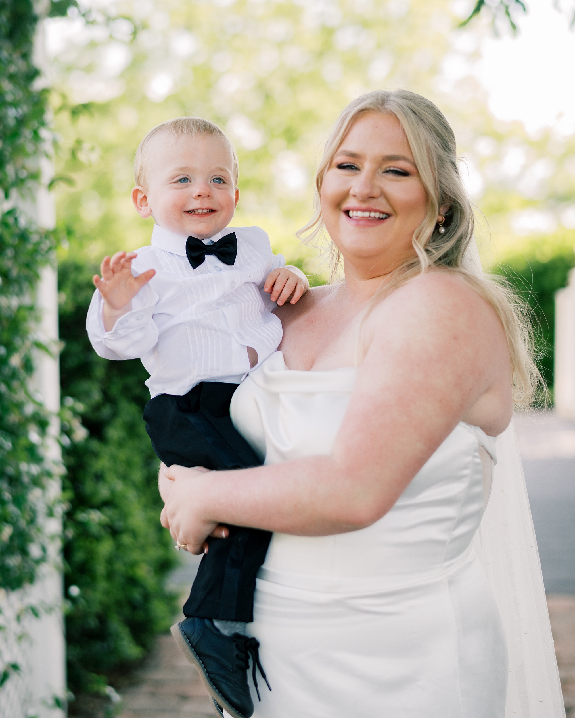 bride stands with son on hip during wedding day