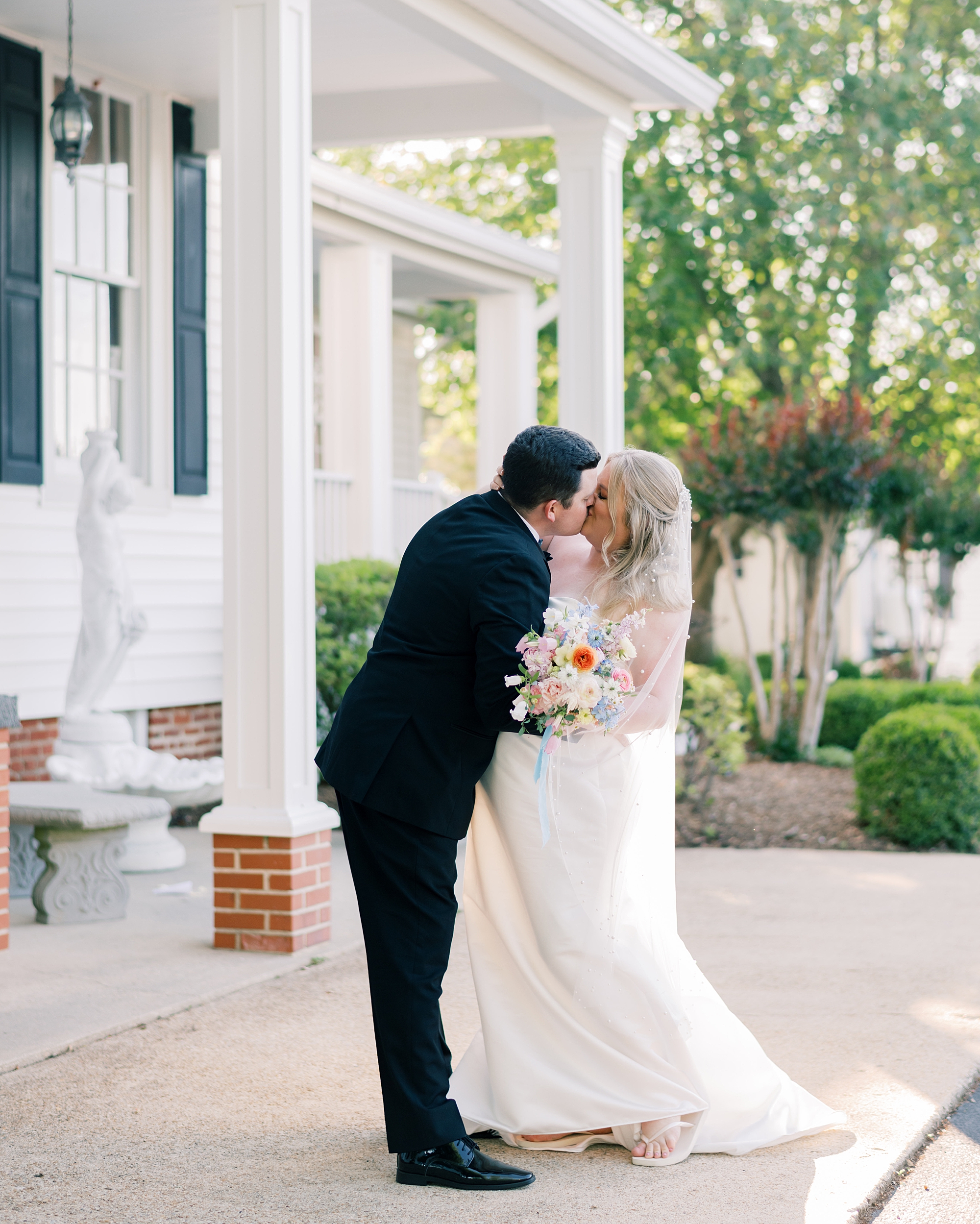 bride and groom kiss outside front porch of Olde Breton Inn