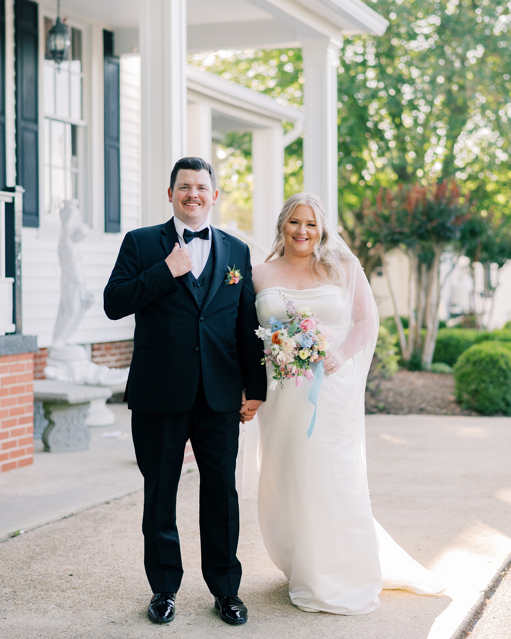 bride and groom stand outside Olde Breton Inn holding hands 