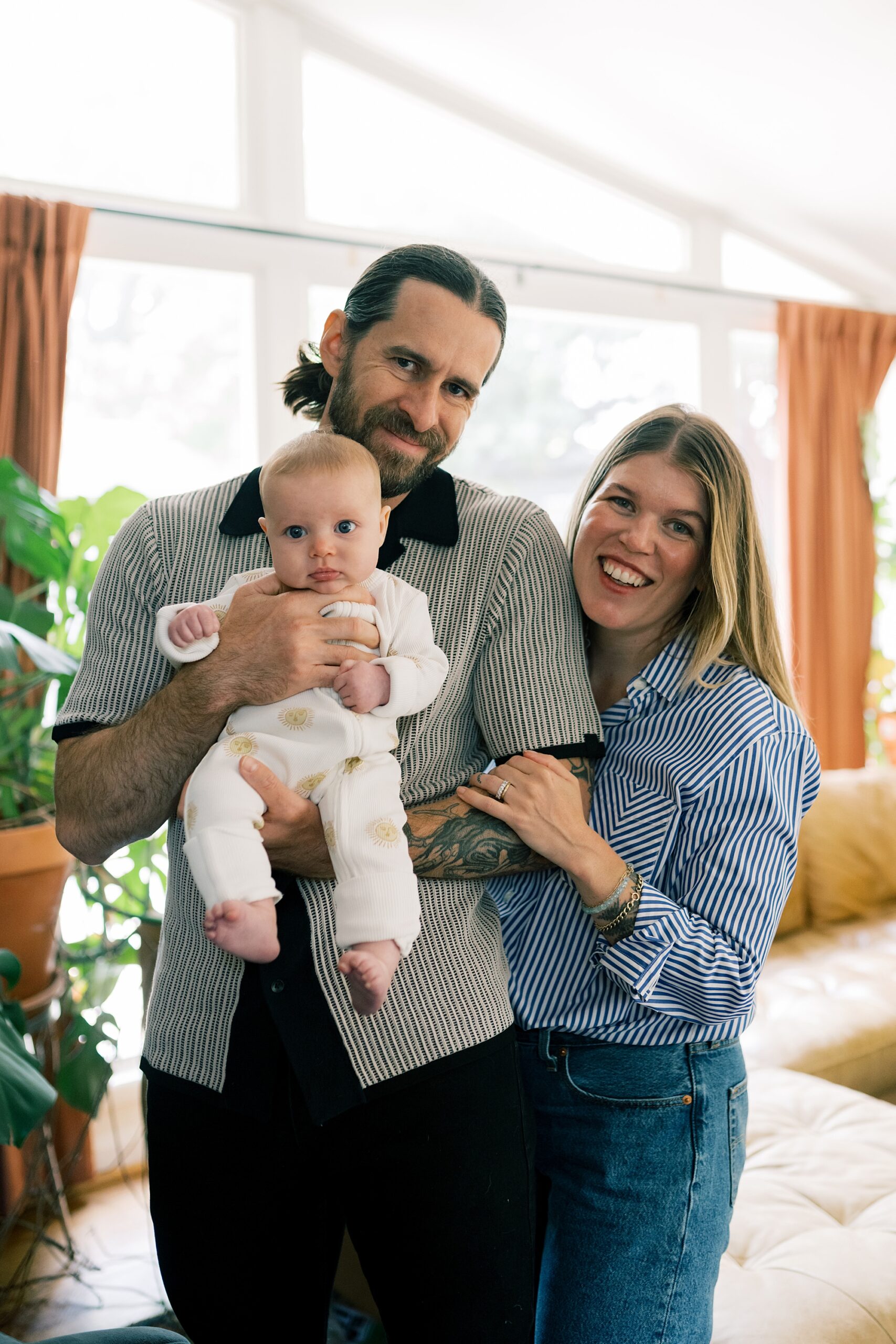 new parents smile with older baby during newborn session in Washington DC home