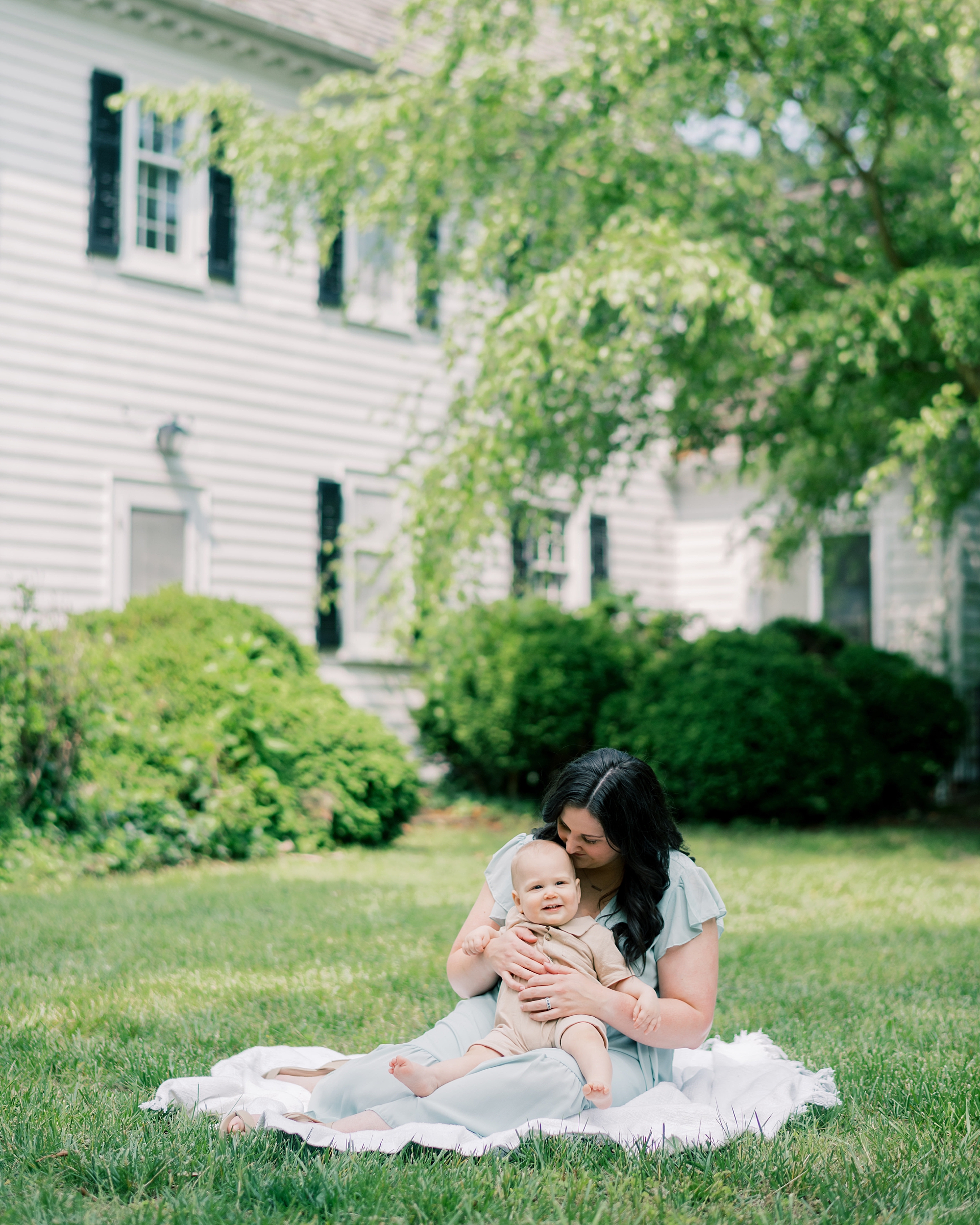 mom sits on blanket with son during family photos
