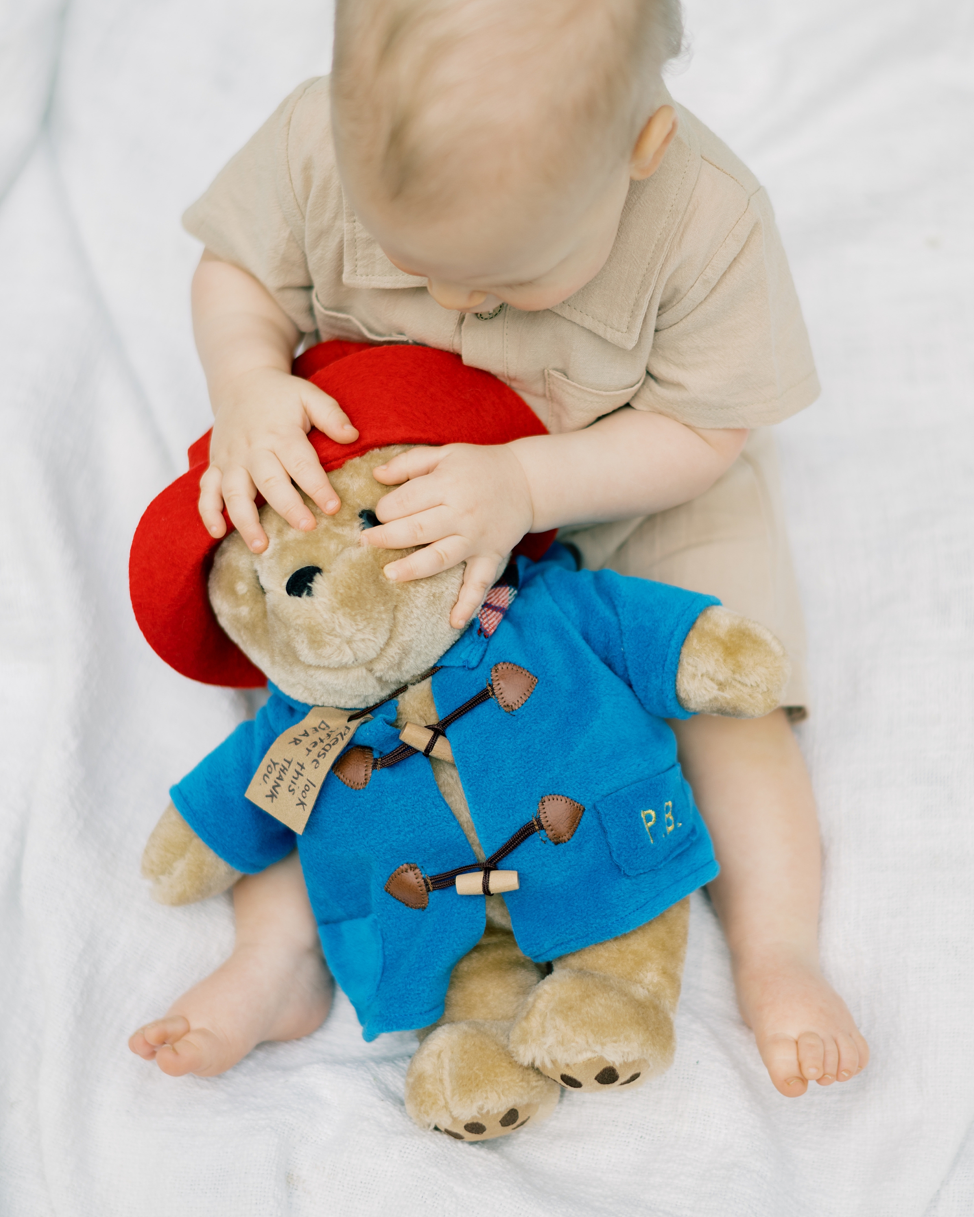 one year old sits on blanket during Paddington inspired first birthday portraits
