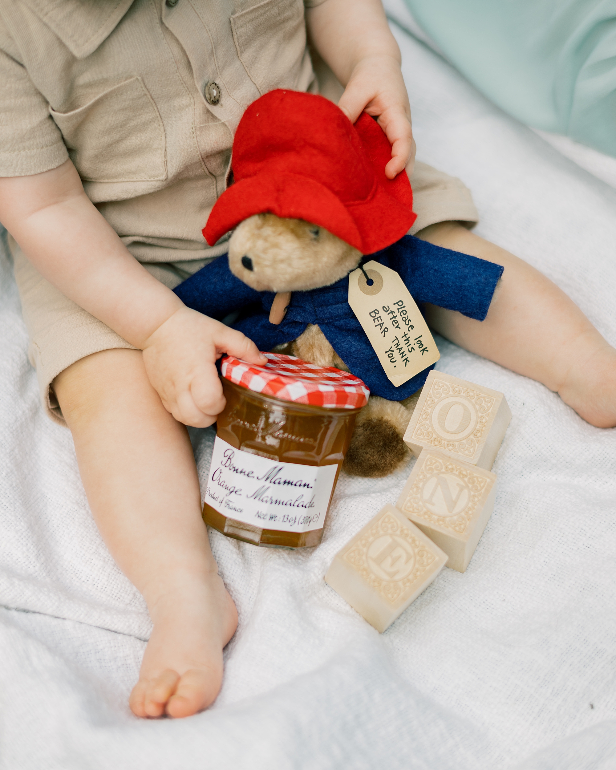 baby holds Paddington bear and jar of marmalade