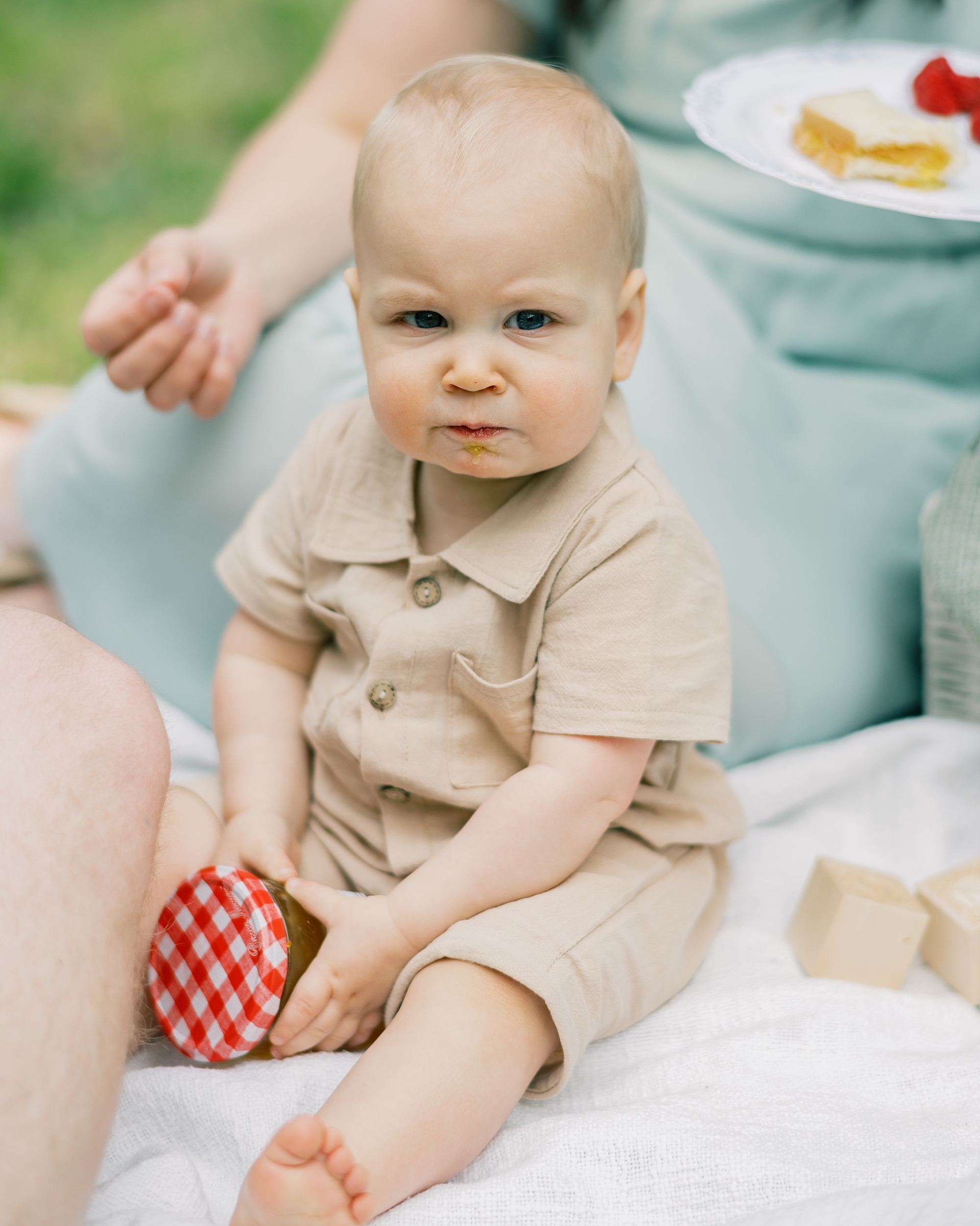 baby in tan outfit sits holding jar of marmalade 