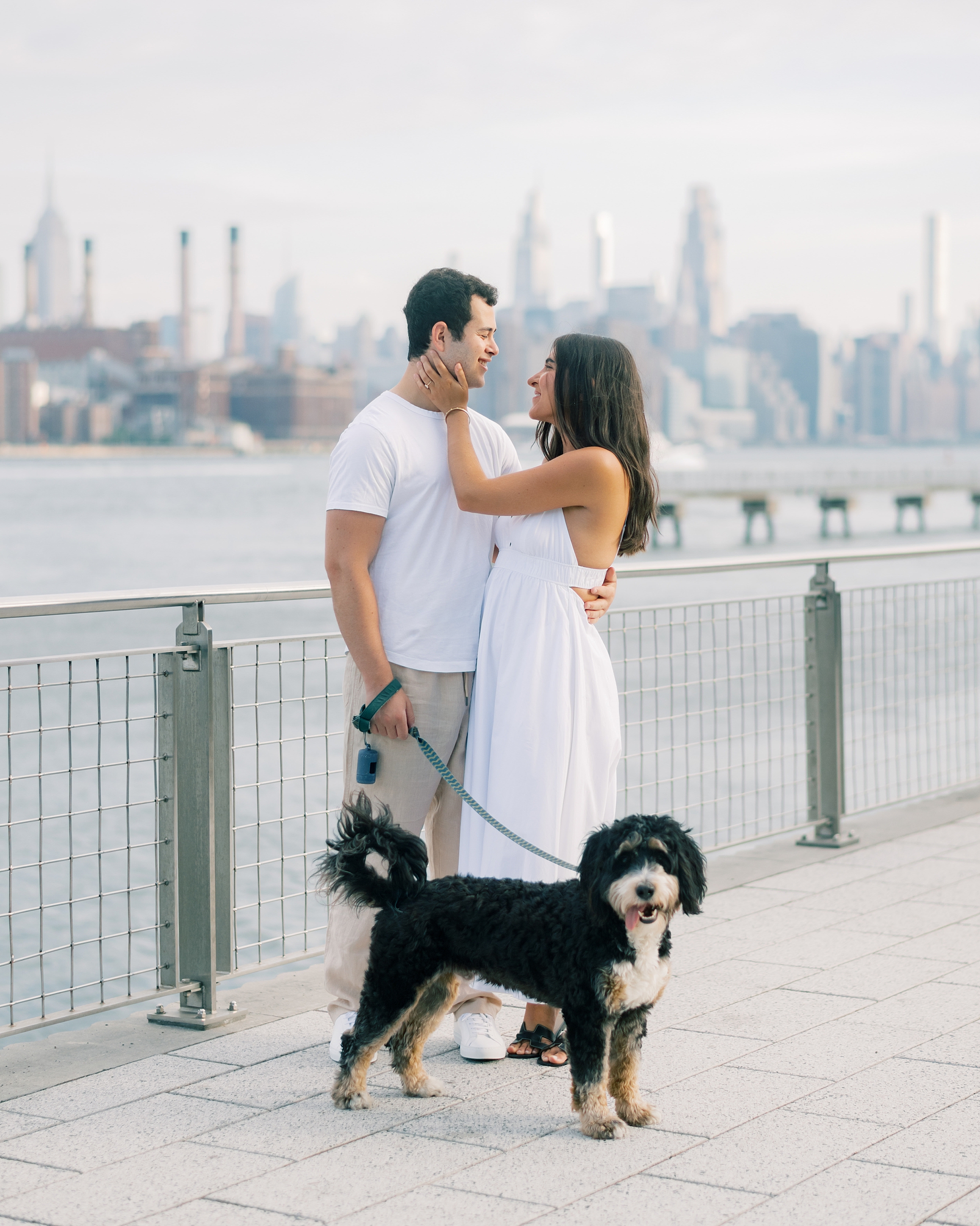 woman holds man's chin smiling up at him at Domino Park
