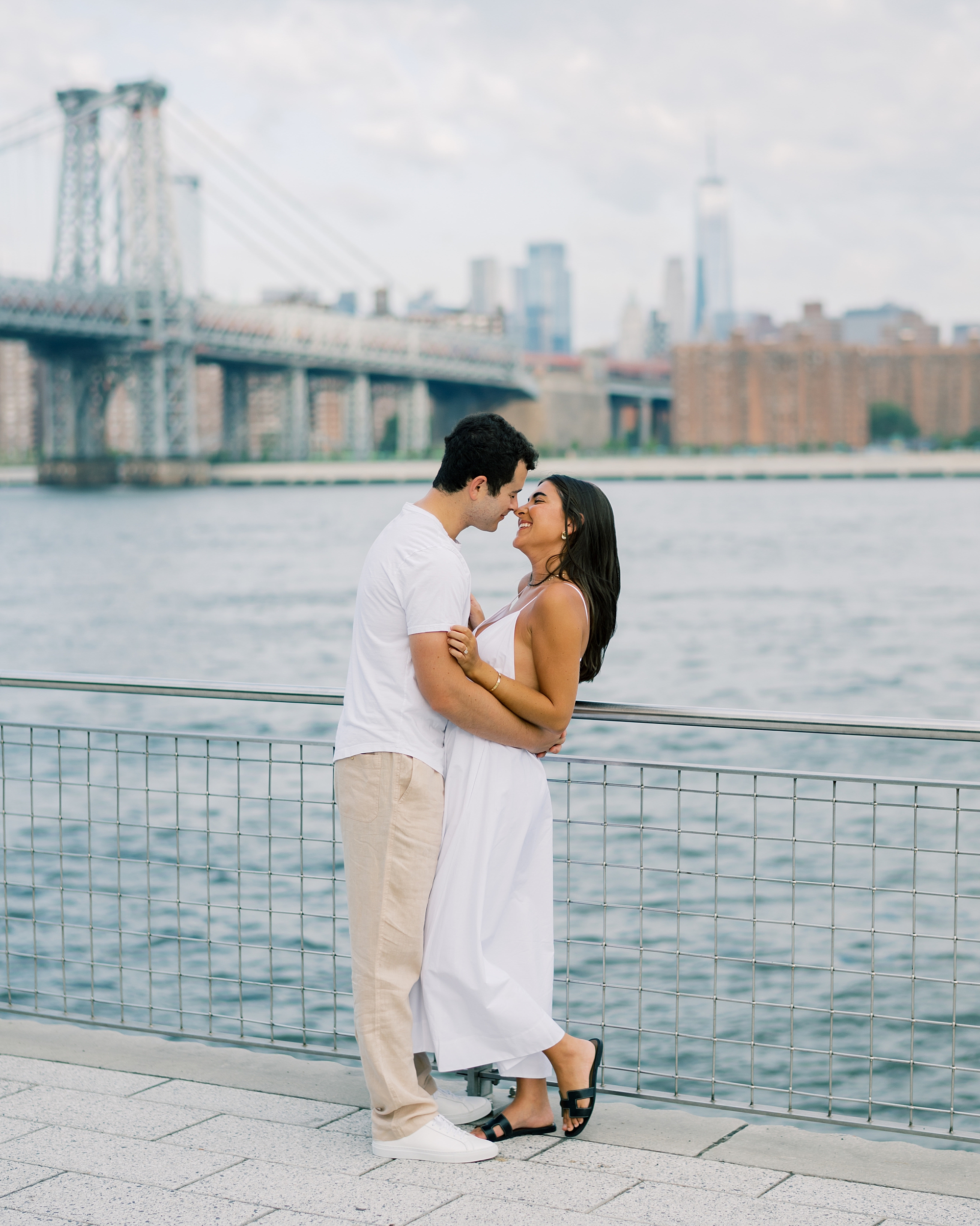 engaged couple stand in front of waterfront in Brooklyn NY during engagement session