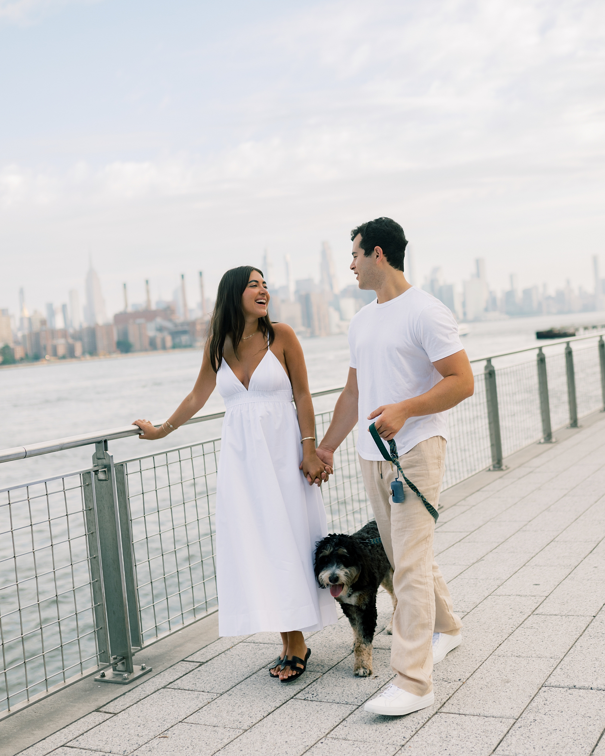 man and woman hold hands walking along pathway in Domino Park