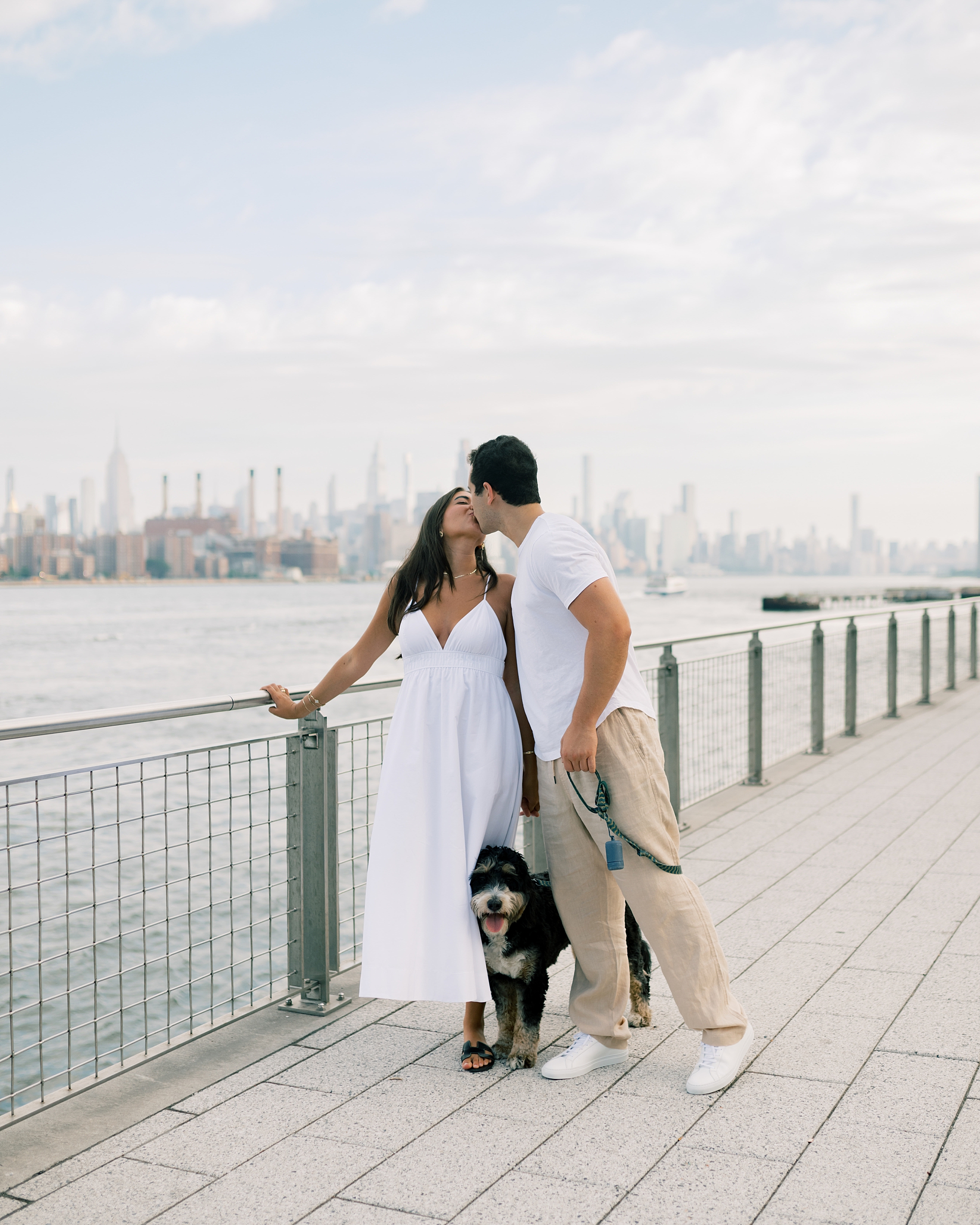 couple kisses along water at Domino Park