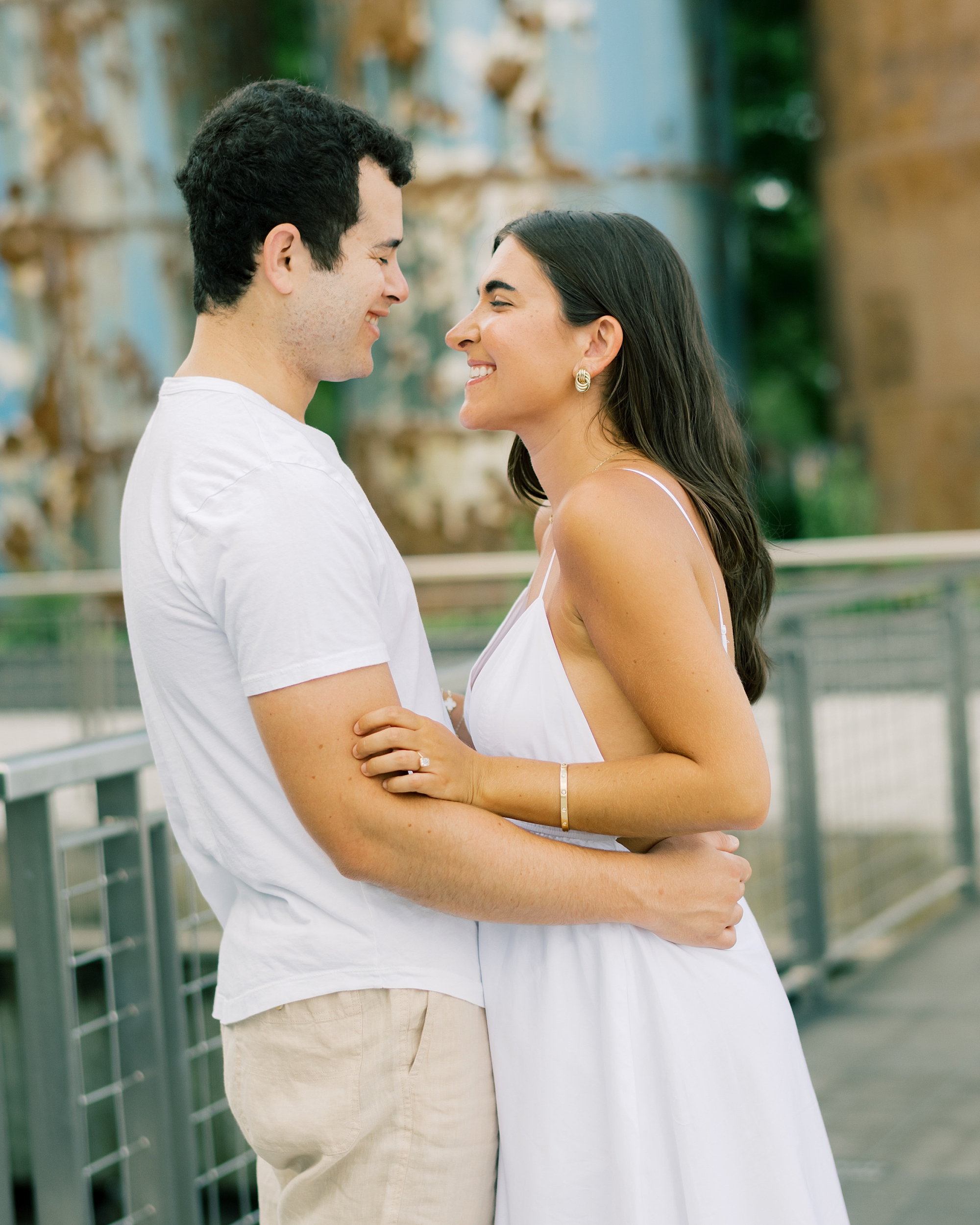 man and woman hug smiling at each other during Brooklyn NY engagement session in Williamsburg