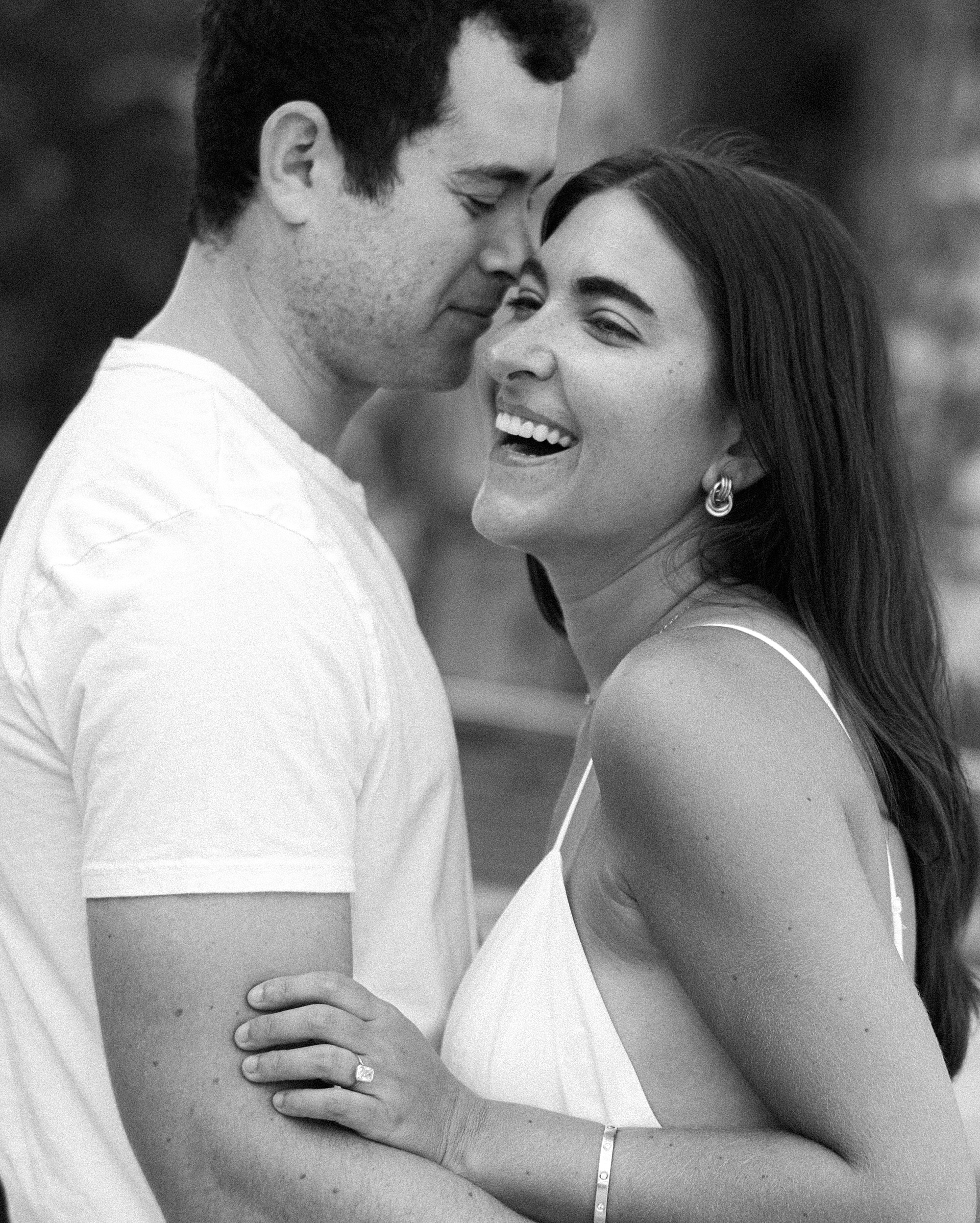man makes woman laugh hugging her during Brooklyn NY engagement session in Williamsburg
