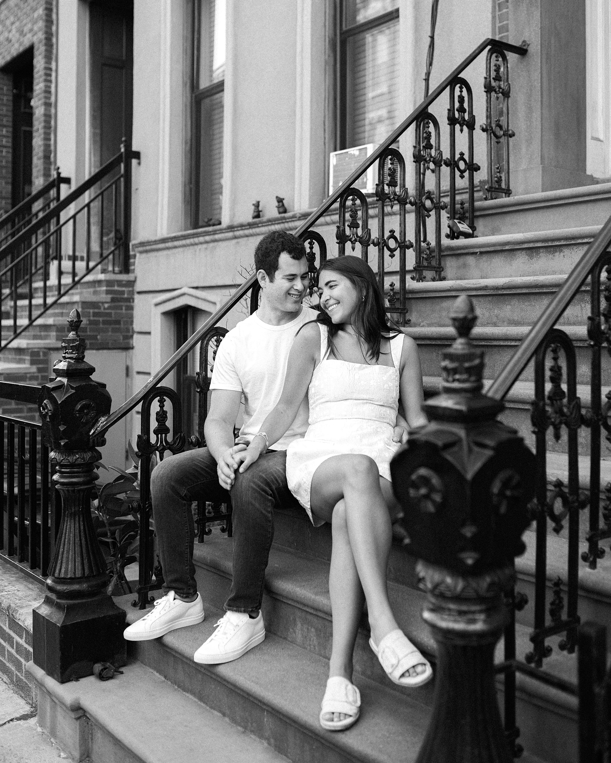 engaged couple sits on steps of Brooklyn brown house 