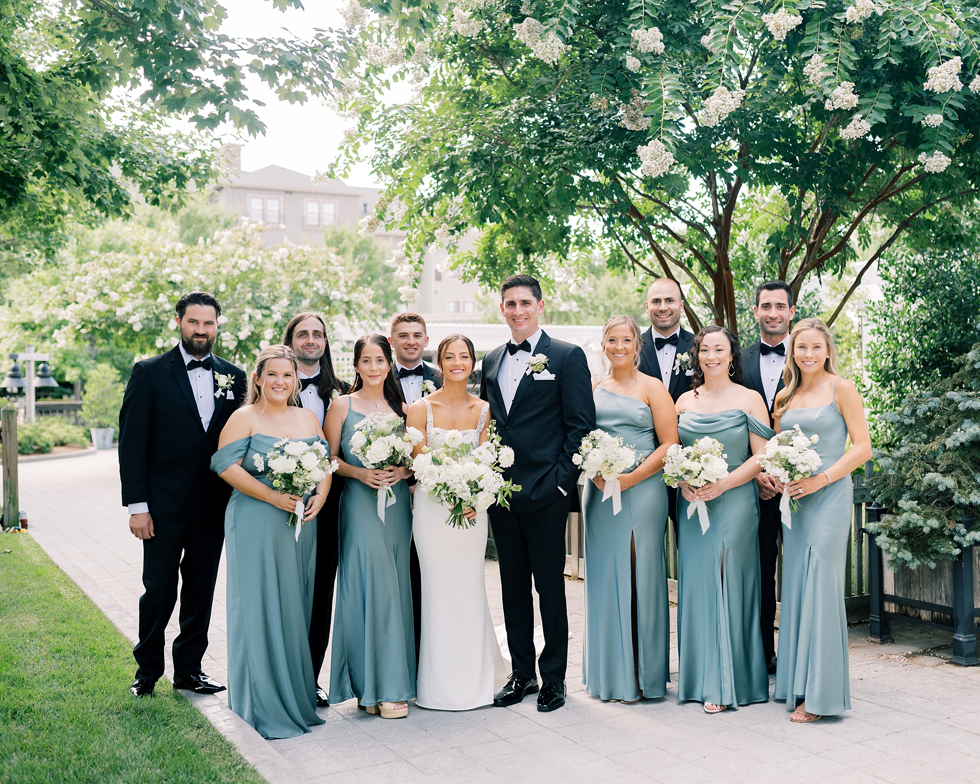 bride and groom stand with wedding party in black and blue attire