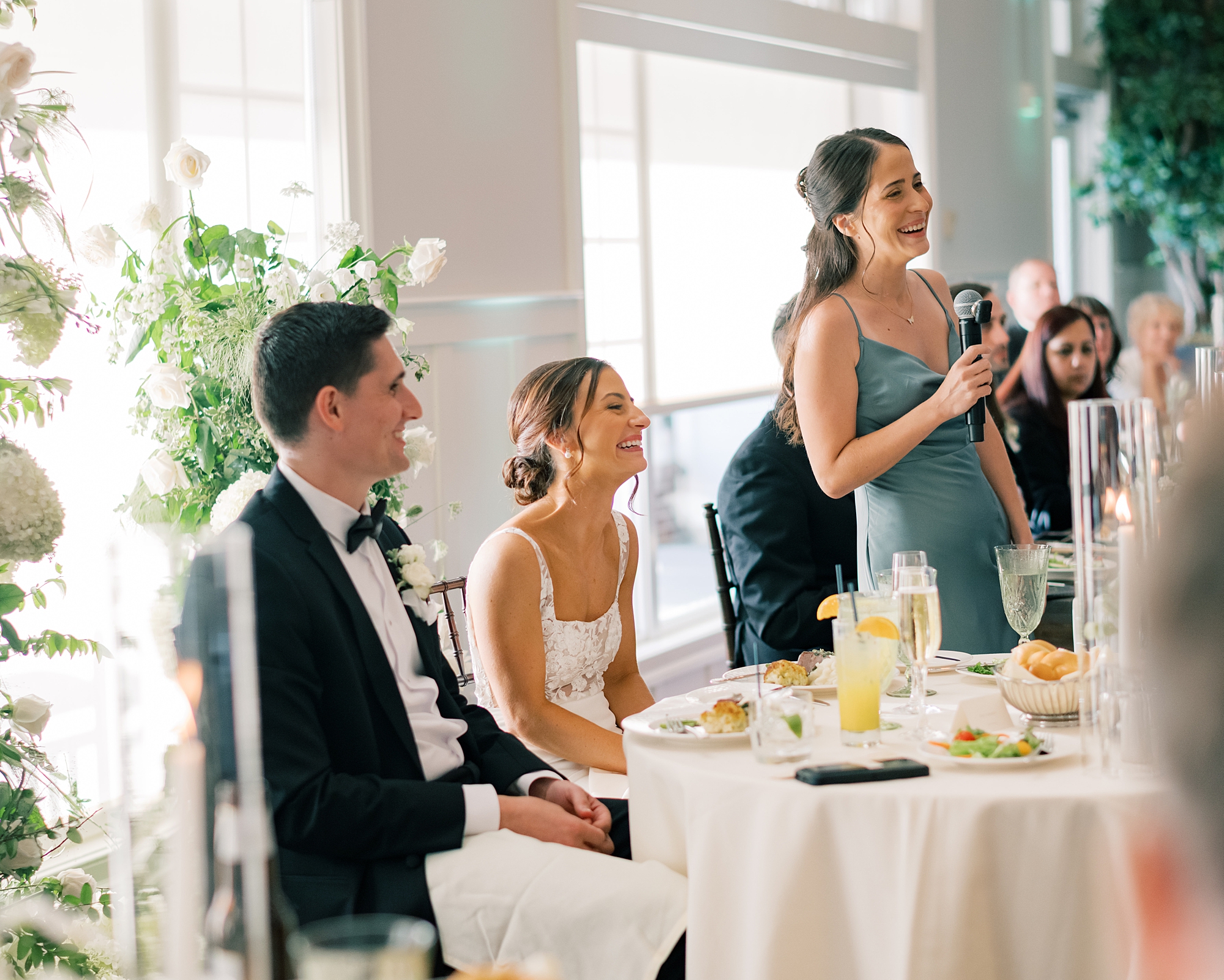 bride and groom listen to bridesmaid give speech
