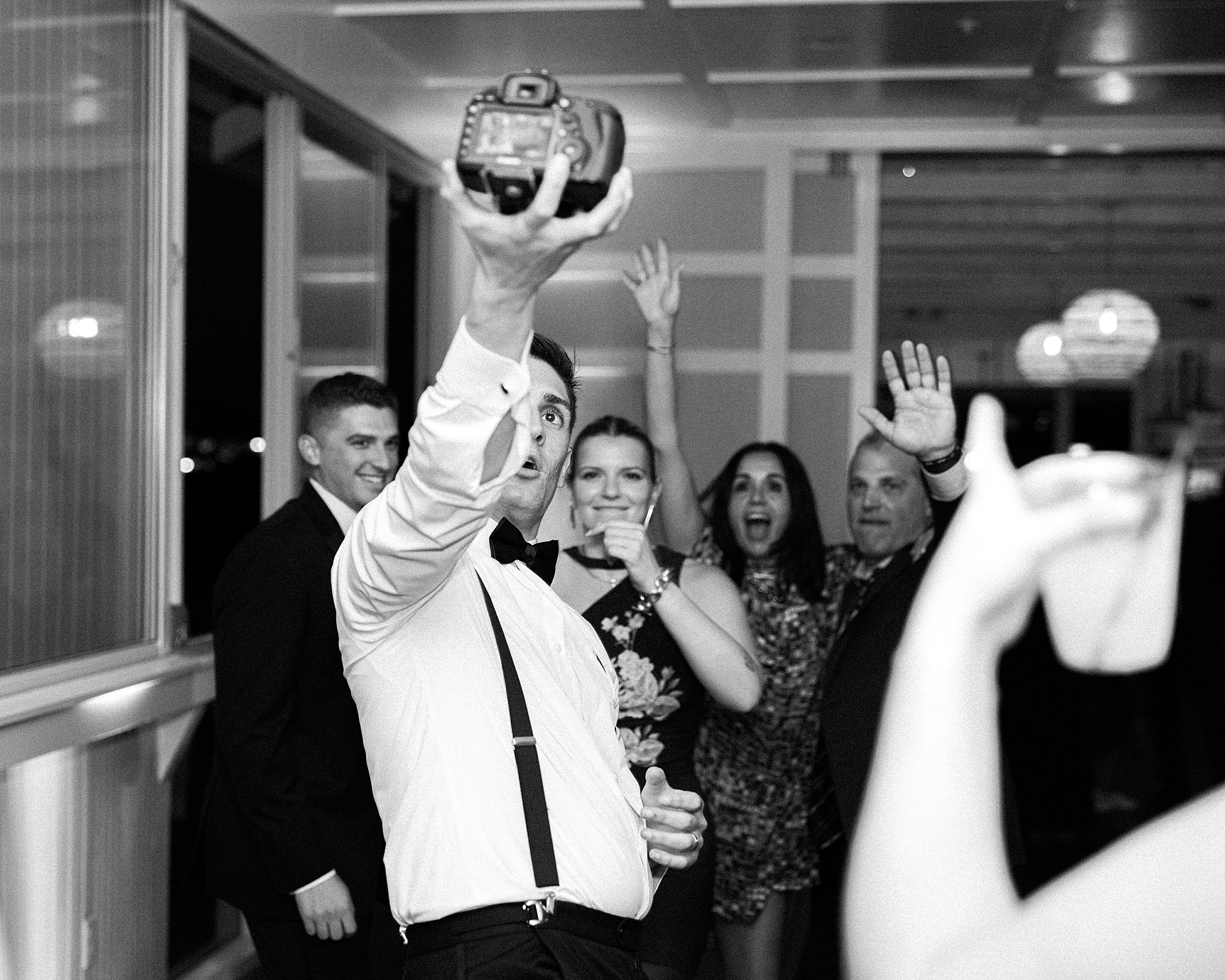 man holds up digital camera taking selfie on wedding reception