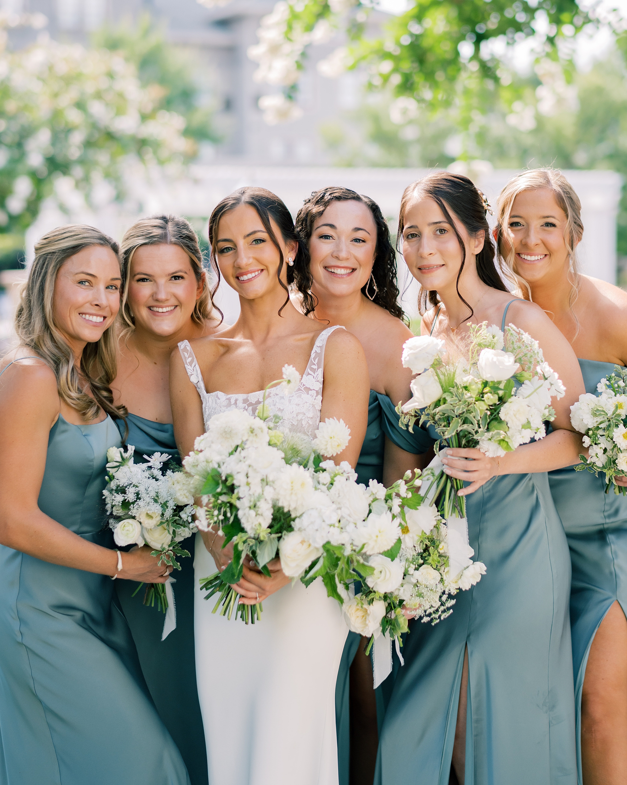 bride hugs bridesmaids in blue dresses with white flowers