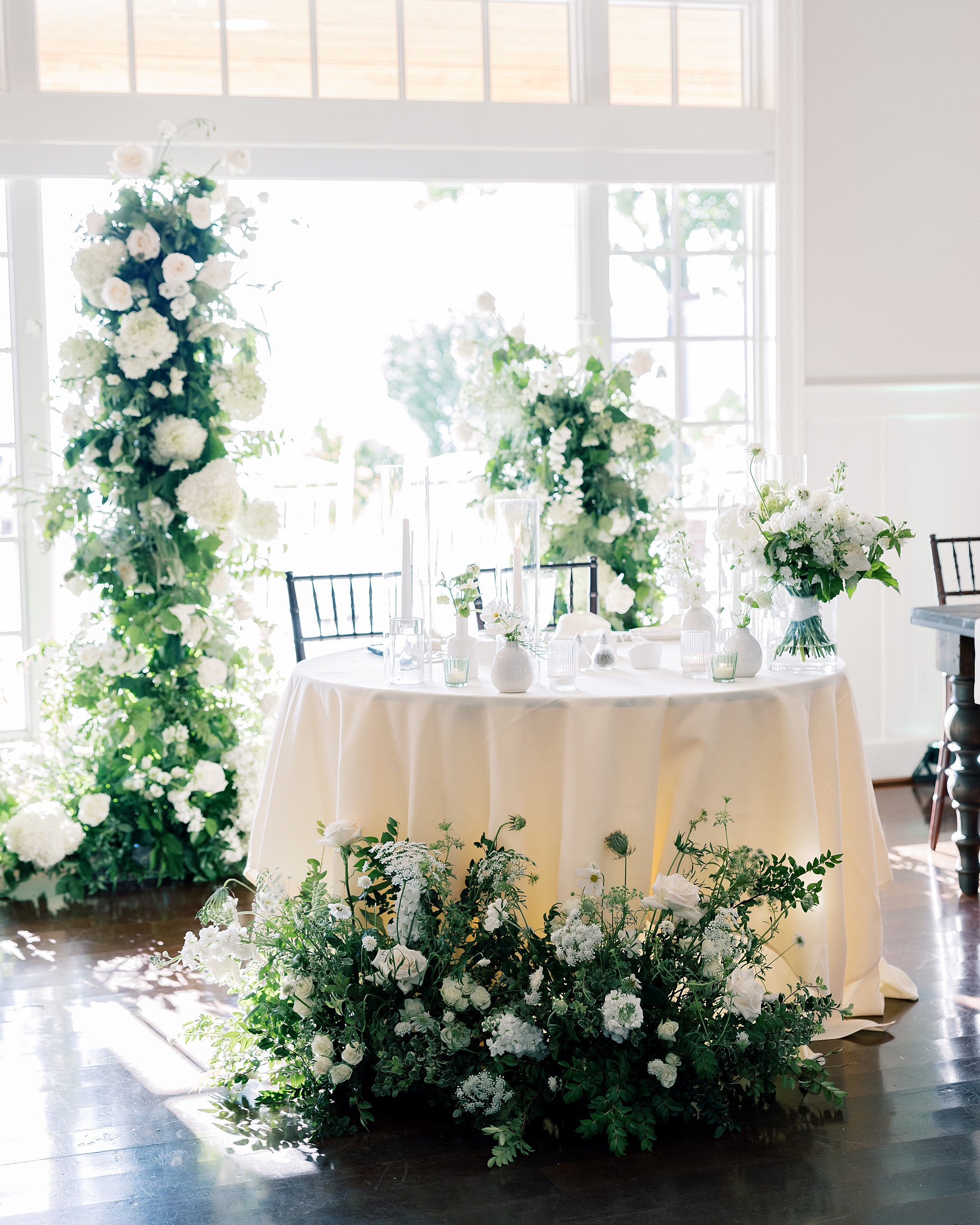 wedding reception sweetheart table with greenery against back window
