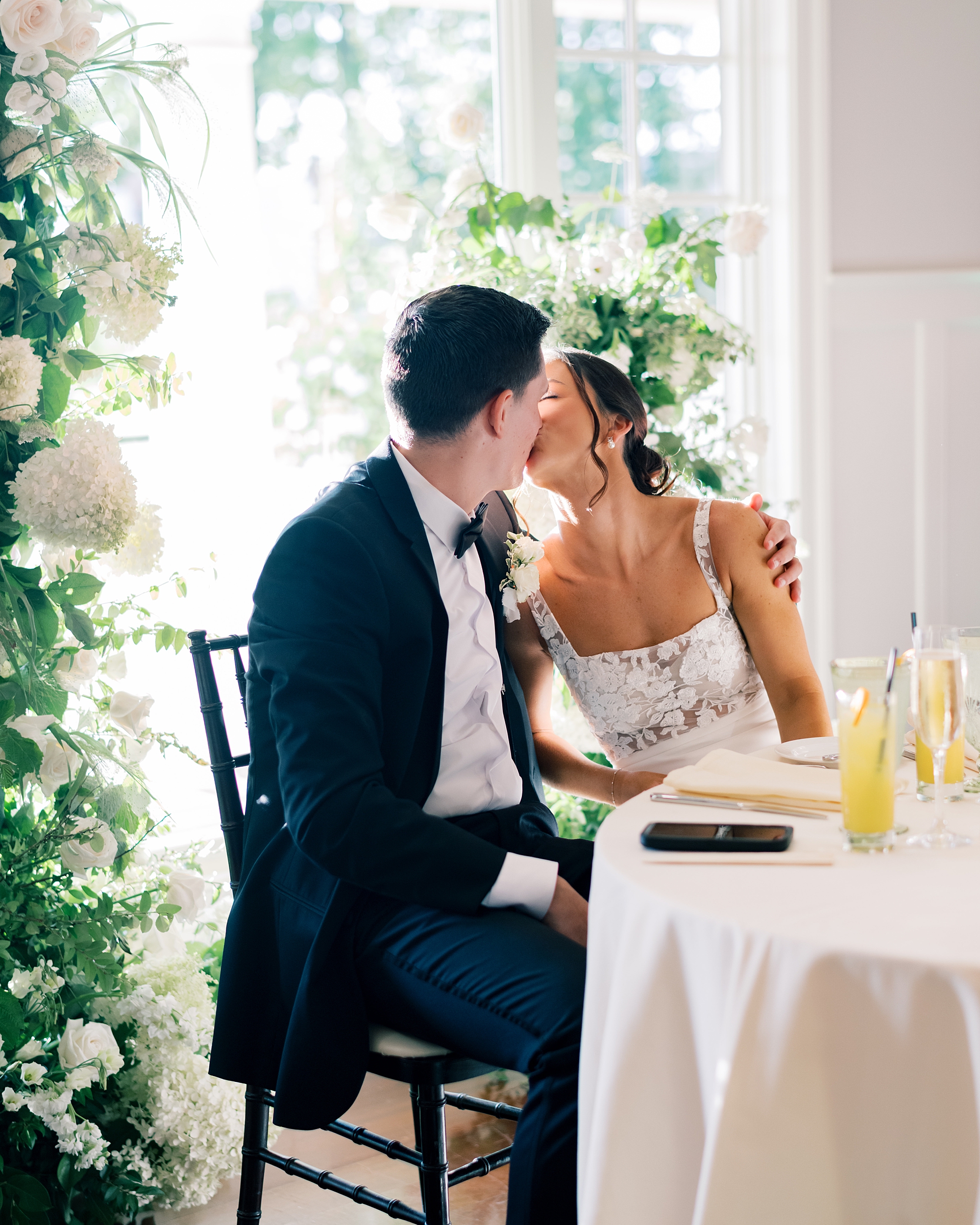 bride and groom kiss at sweetheart table during wedding reception
